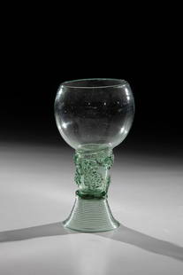 Roman: Romans, Germany or Netherlands, 17th century. Light green, slightly blistered glass with tear. Woven foot. On the shaft, which is open at the top, two rows offset by appliquéd berry nubs. Below the