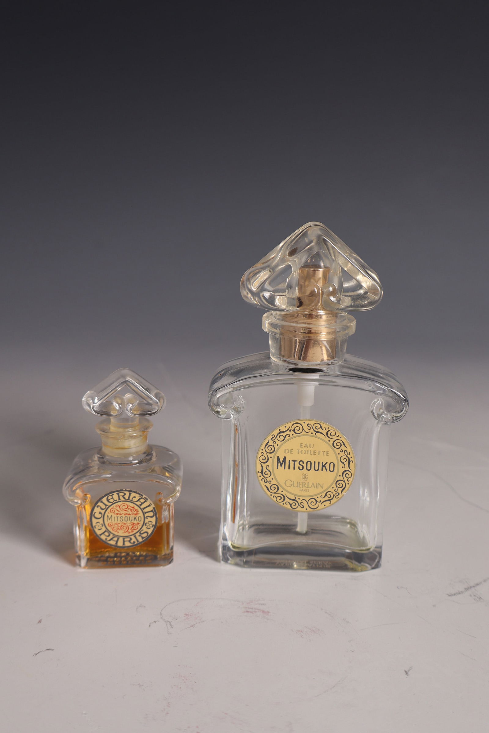Pair of ''Mitsouko'' bottles for Guerlain: Two bottles ''Mitsouko'' for Guerlain Raymonde Guerlain (design), Cristallerie de Baccarat (execution), 20th century Colourless glass, moulded, partially ground and polished. Original sticker from the