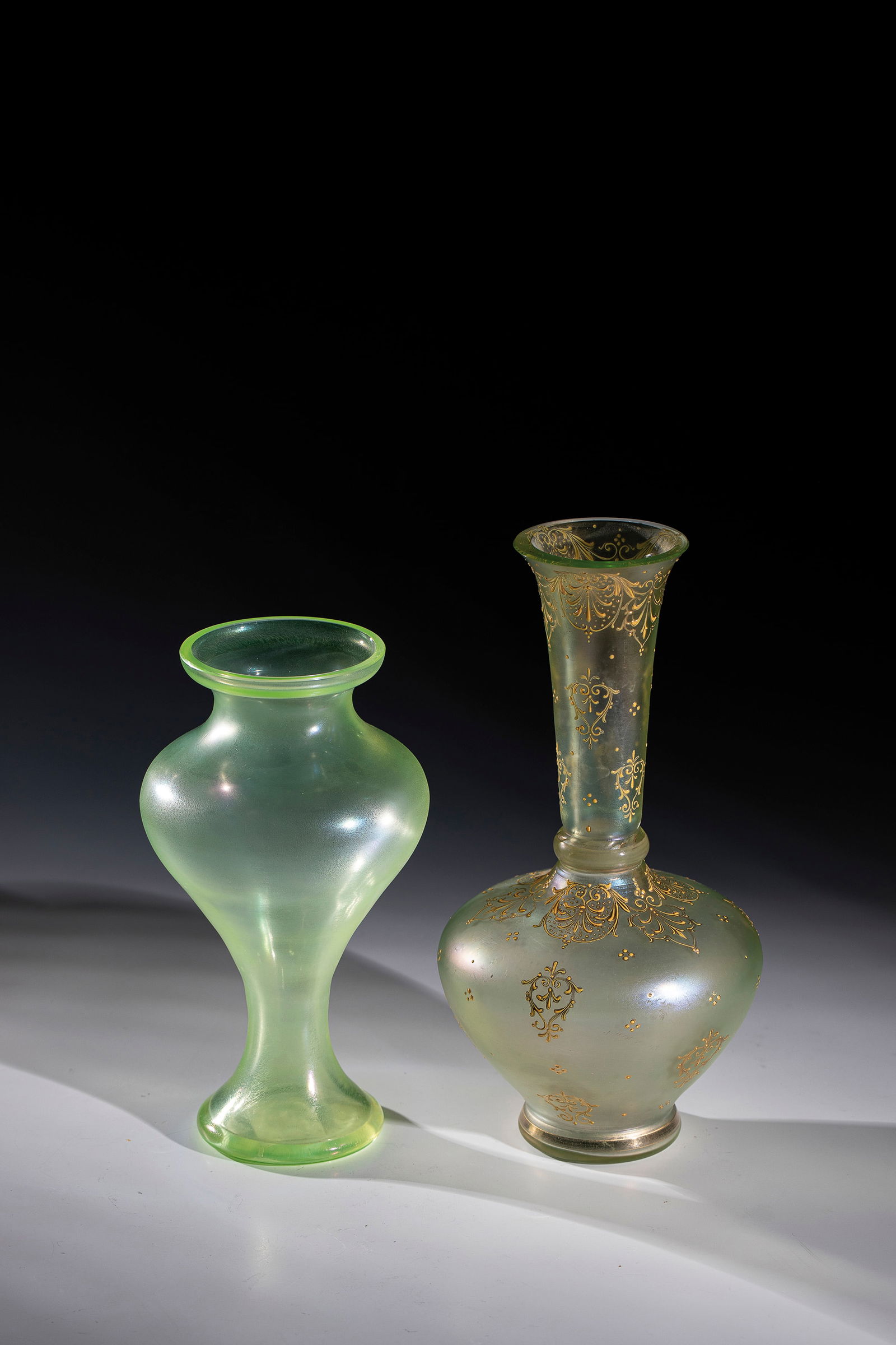 Two vases: Two vases Loetz Wwe., Klostermühle, 1910 Light green uranium glass. A vase with all-round decoration in relief and polished gold painting: stylized foliage. Iridescent. H. 18.5 or 22.5 cm.Zwei Va