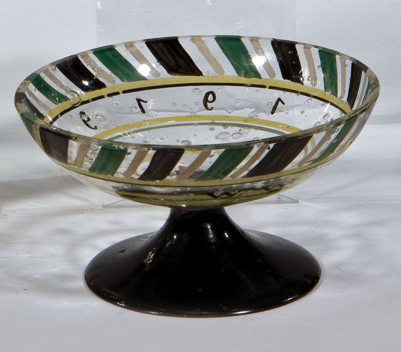 Kleine Fußschale: Kleine Fußschale Maria Likarz (Entwurf), Wiener Werkstätte, 1919 Farbloses, stark blasiges Glas mit Schwarzlot, grünem und schwarzem Transparentemail. Dekor: geometrische Ornamente im Rapport. Auf