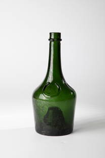 Liqueur bottle ''BENEDICTINE'': Liqueur bottle ''BENEDICTINE'' 20th century Green glass with a raised bottom. Inscription in relief on the slightly widening wall. Long tubular neck with applied thread. H. 26 cm