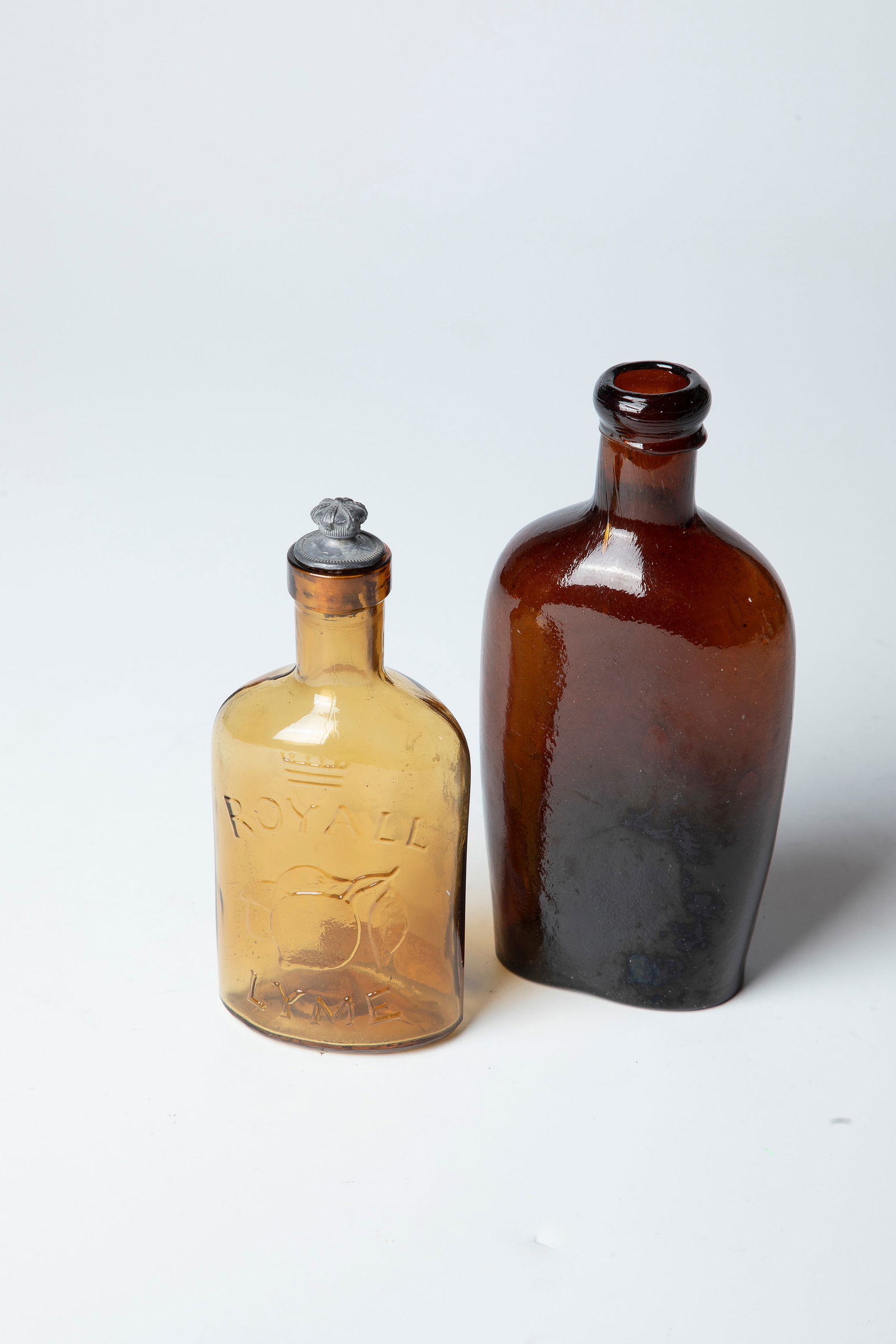 Two flat bottles: Two flat bottles England, 19./20. Century Bernstin-coloured pressed glass. One in relief inscribed ''Royal Lyme'' with a pewter-framed cork. H. 13 or 16 cm