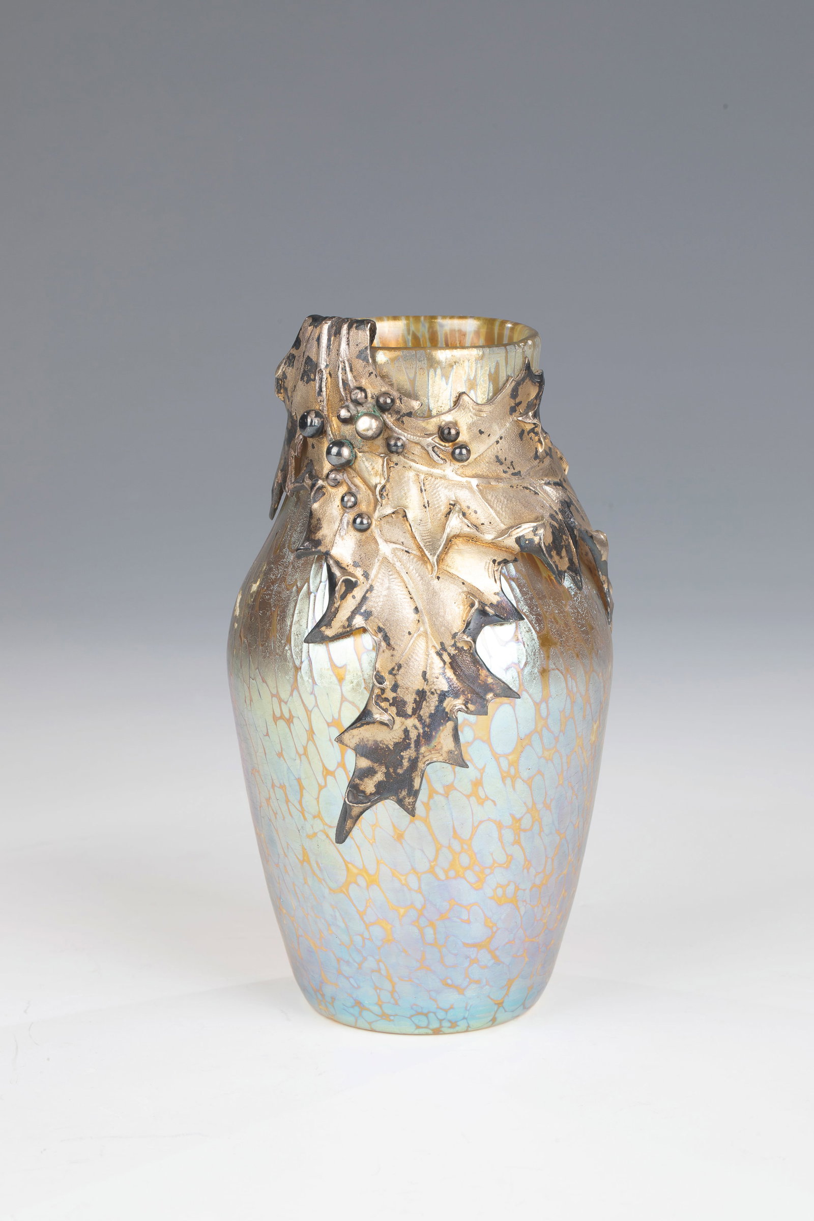 Small vase '''Candia Papillon'' with silver mount: Small vase '''Candia Papillon'' with silver mount Loetz Wwe., Klostermühle, around 1900 Colourless glass with crumb melting in silver yellow. Matt iridescent. On the front side with a silver mount in