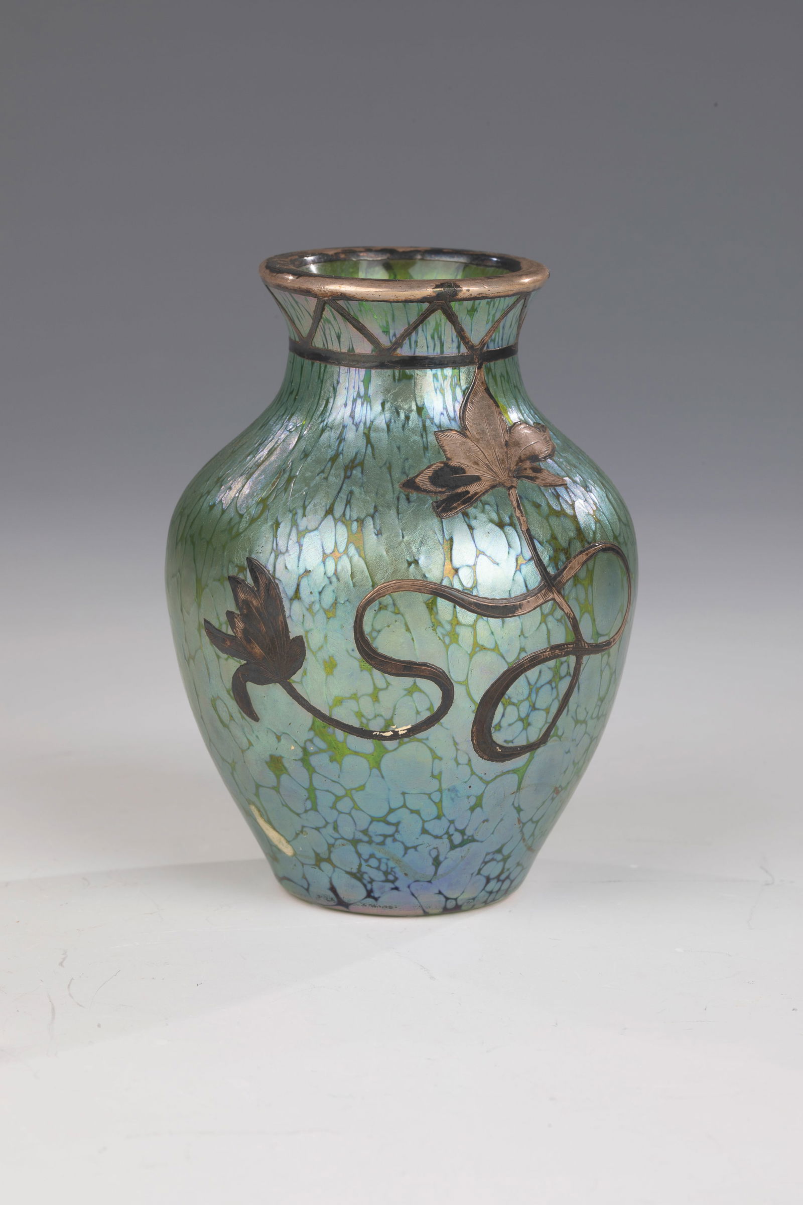 Small vase ''creta Papillon'' with silver plating: Small vase ''creta Papillon'' with silver plating Loetz Wwe., Klostermühle, c. 1900 Green glass with melted silver-yellow crumbs. Reduced and matt iridescent. Visible side in galvanized fine silver:
