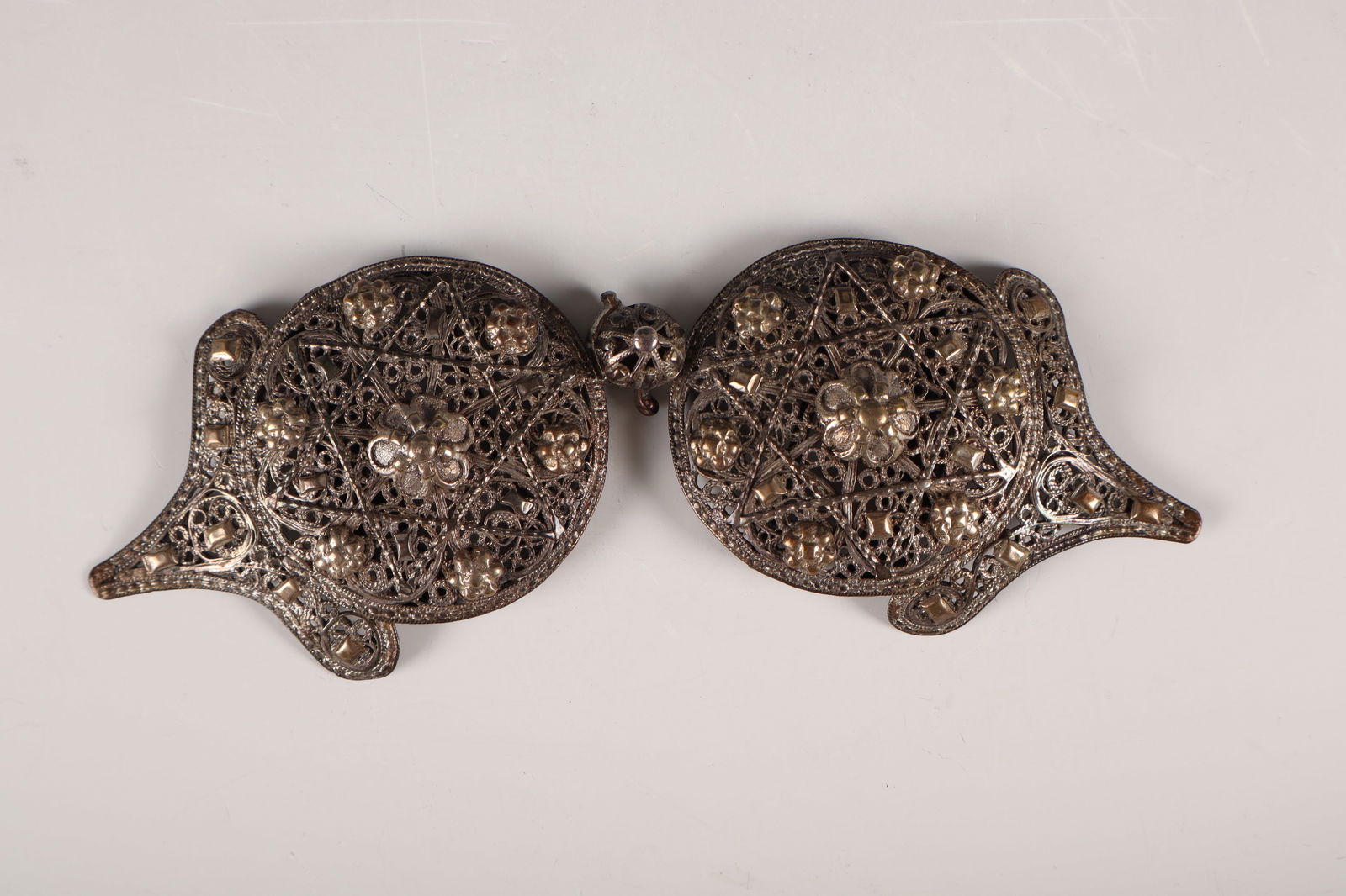 Traditional belt buckle: Traditional belt buckle 19th/20th century silver filigree. Bipartite. Round shape with an appliquéd Star of David and stylised, multi-petaled flowers in between. Unmarked. L. 19.5 cm. 92 g.