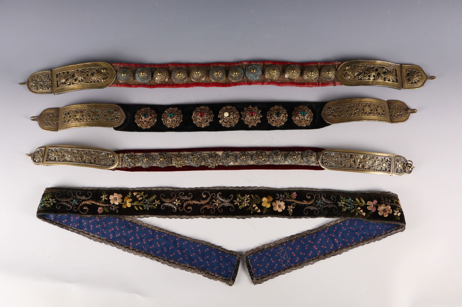 Three traditional belts for children and an embroidered traditional ribbon: Three traditional belts for children and an embroidered traditional ribbon Transylvania, 18th / 19th century. Different materials, partly brass. Bucks mounted on velvet ribbons between different clasp