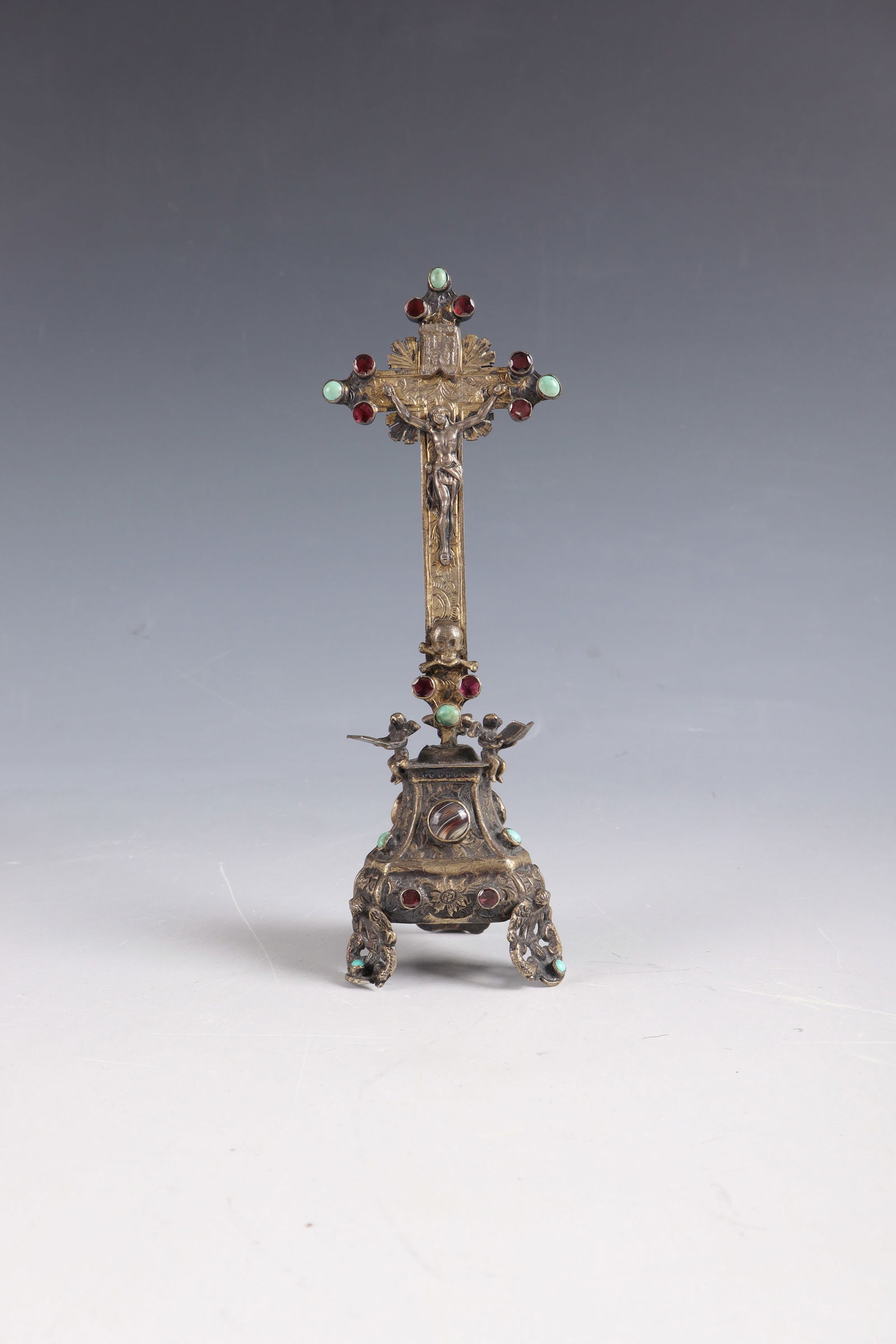 Crucifix: Crucifix Probably Austria/Hungary, 18th/19th century Gold-coloured metal, partly vegetable-engraved. Depiction of angels reading from the Gospel. Set of semi-precious stones. Minimally damaged. H. 14.