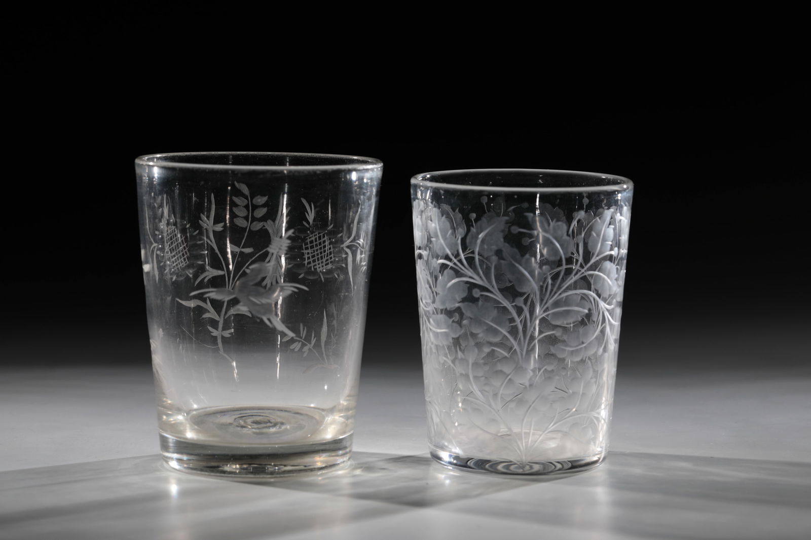 Two cups: Two goblets, 19th century, colourless glass with tear-off. Engraved decoration on the slightly conically widened wall: stylised sunflowers and birds or leaf-filling decoration. 11 or 12 cmZwei Becher