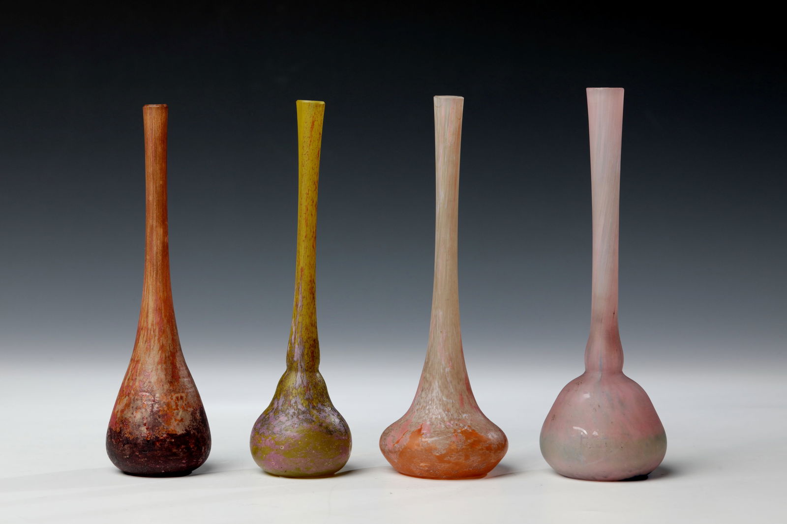 Four long-neck vases: Four long-neck vasesVier Langhalsvasen Daum Frères, Nancy, um 1910/15 Farbloses Glas mit Farbaufschmelzung in Gelbgrün, Rosaorange und Braunviolett, säuremattiert. Auf der Wandung bezei