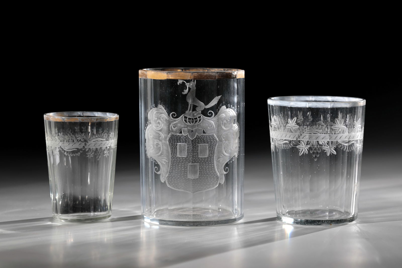 Mixed lot of three cups: Mixed lot of three cups of giant mountains, 18th century Colourless, multi-faceted glass. Frontal matt and brightly cut coat of arms with three drums and armour crowned by a fox. Gold-plated lip rim c