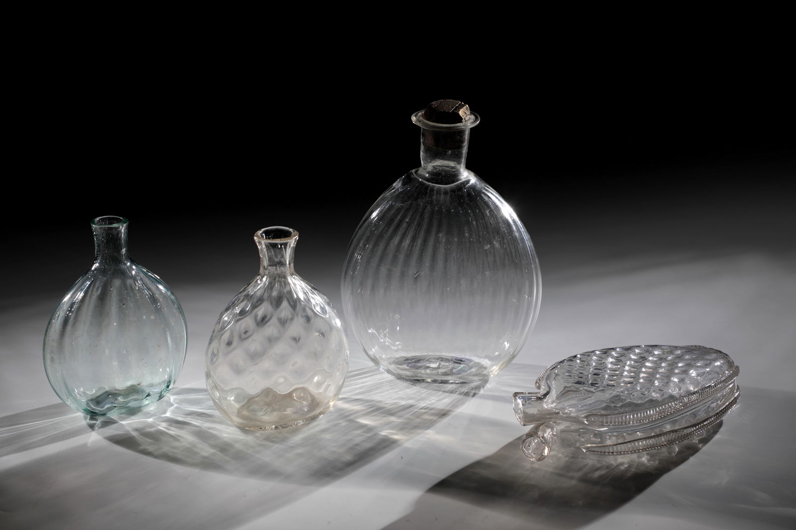Mixed lot of three pouch bottles and a double bottle: Mixed lot of three pouch bottles and one double bottle Alpine 18th century Colourless glass with tear-off and slightly raised bottom. Flattened wall with longitudinal optical or diamond decoration. Tu