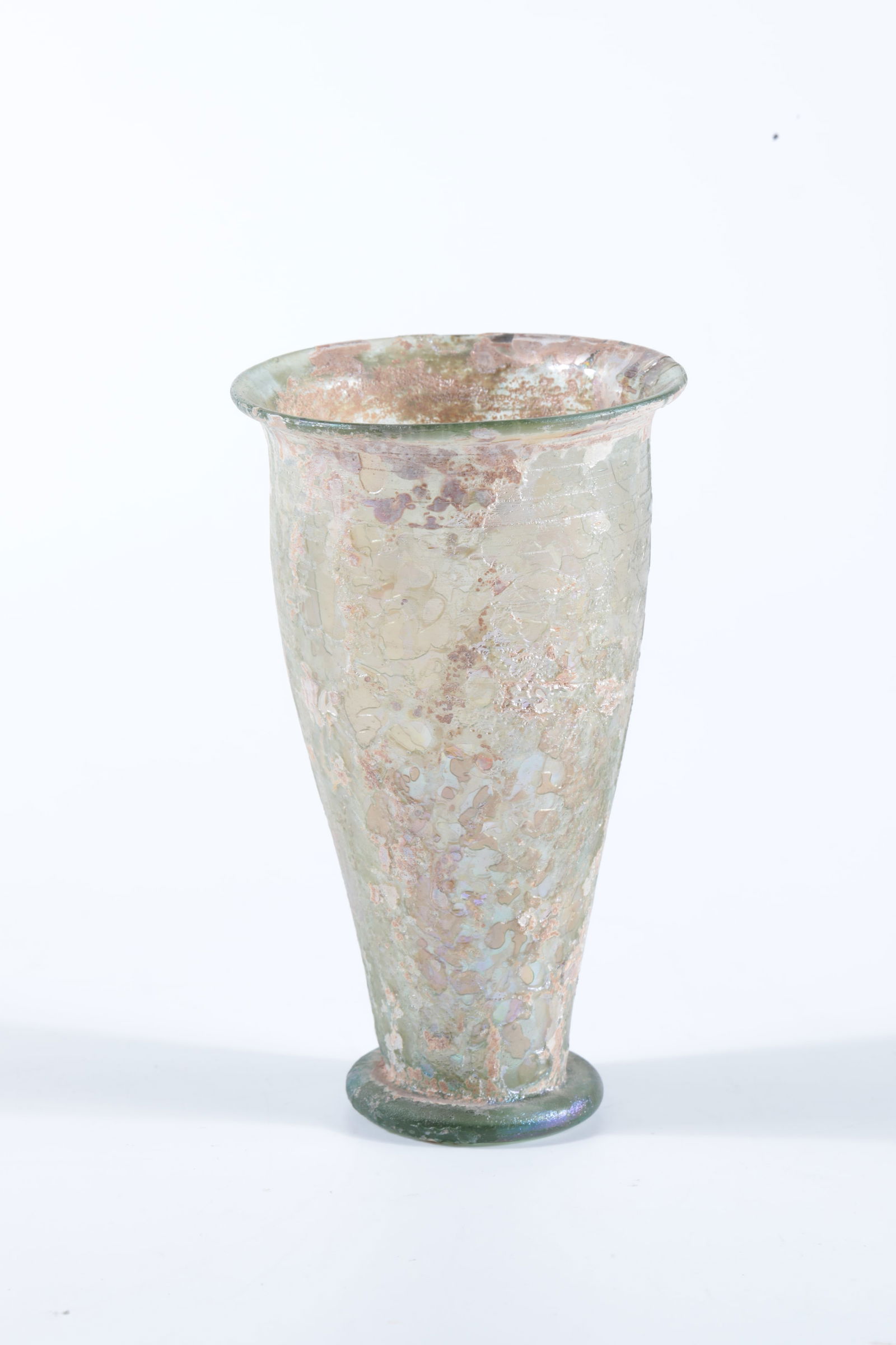 Tumbler: Tumbler Roman, 2nd century AD. Ground find. Green glass with patina and iridescent. Compressed stand with slightly raised floor. Conically widened wall with protruding muzzle edge. H. 11.5 cm