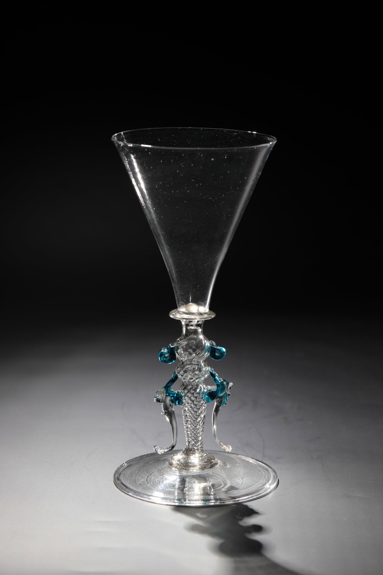 Wing glass: Casement glass Façon de Venise, 17th century Colourless, thin-walled glass with demolition. Disc base with the edge folded downwards. Oblique optically blown baluster shaft double-constricted. On it
