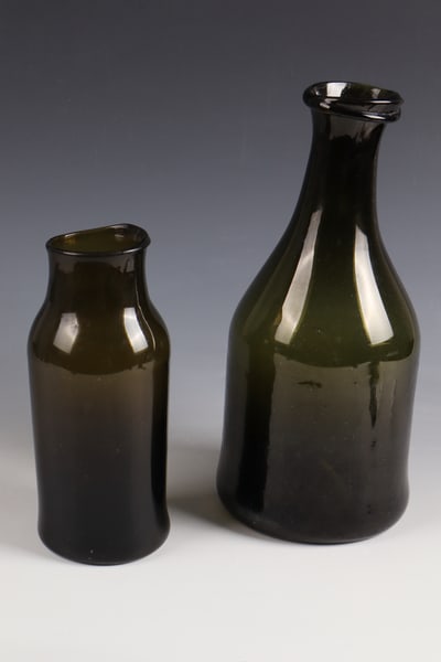 Two storage vessels: Two storage vessels, France, 19th century, olive-green glass with tear-off. Club-shaped or cylindrical wall. One with a glass thread placed below the edge of the mouth. H. 22 or 32 cm