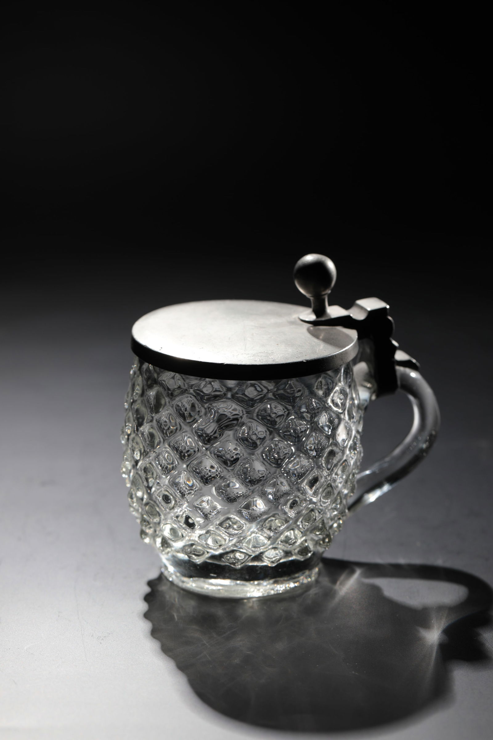 Miniature jug with wart decoration: Miniature jug with wart decoration Southern Germany, 19th century Colourless glass with tear-off. On an appliquéd handle, tin lid with ball as thumbrest. H. 8 cm