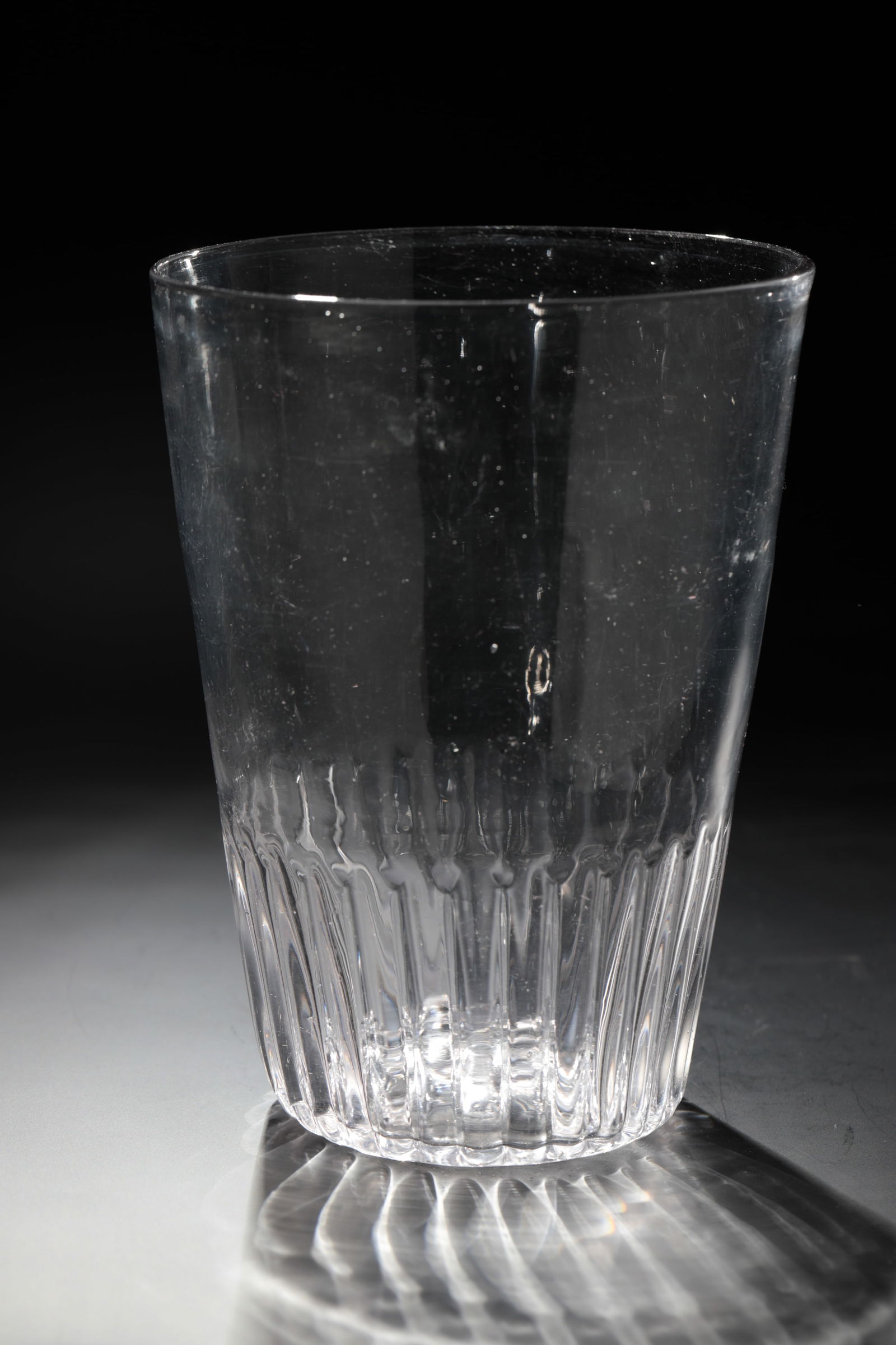 Large rib cup: Large ribbed cup Germany, 18th century Colourless, slightly manganese-tinged glass. Twelve-pointed ground star. The base of the conically widened wall is ribbed. h. 19.5 cm Cf. lit.: Sammlung Birgit +