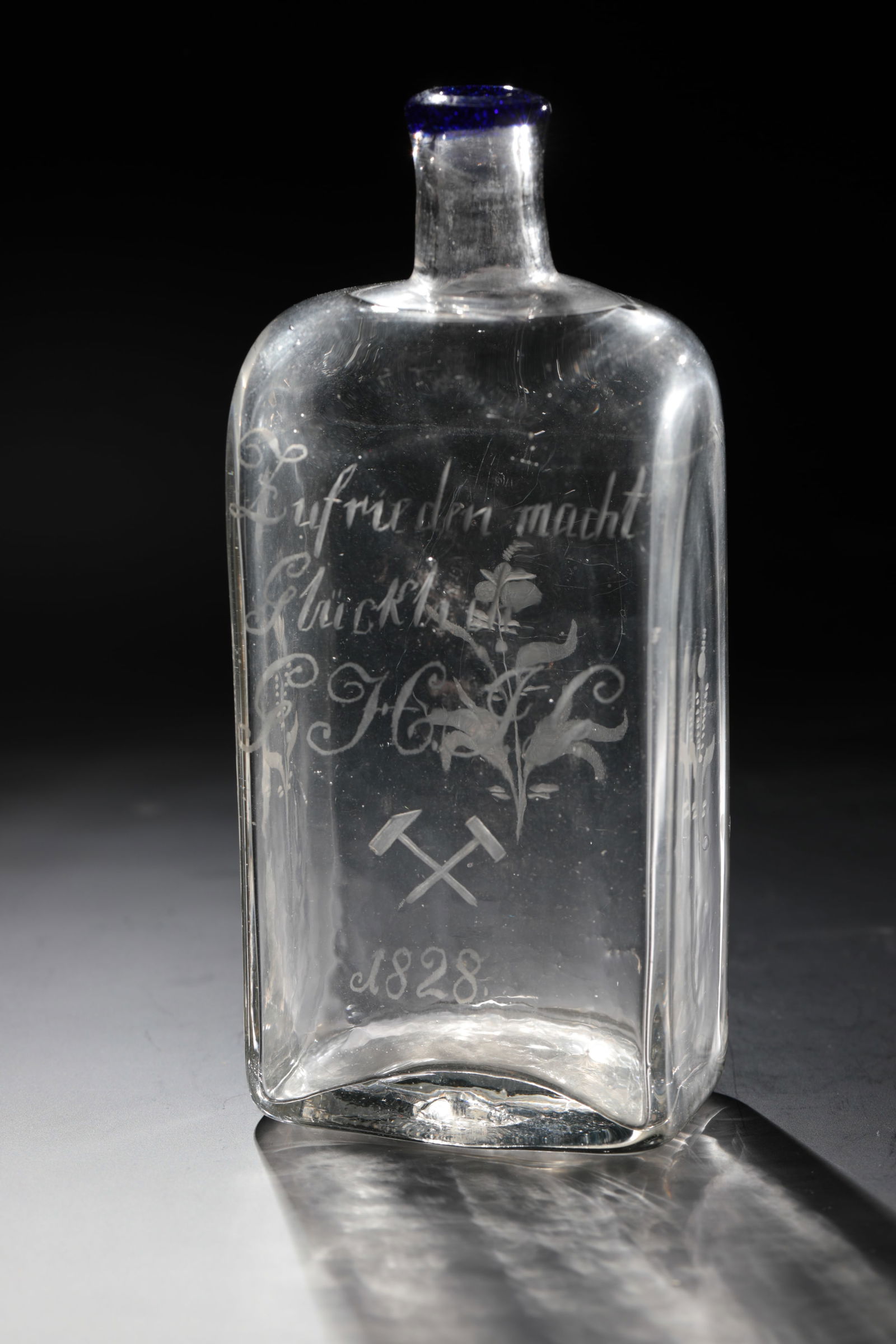 Mining Bottle with Blue Rim: Mining bottle with blue rim Northern Germany, dated 1828 Colourless glass with tear-off. Rectangular wall in cross-section. The inscription engraved on the front above the year ''1828'' with crossed