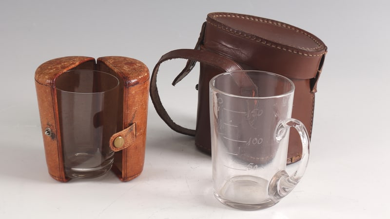 Two travel mugs in leather case: Two travel mugs in a leather case France E. 19th / A. 20th century Consisting of mug with handle with gradation and engraving: ''Vichy'' as well as cylinder cup. H. 7.5 or 9 cm