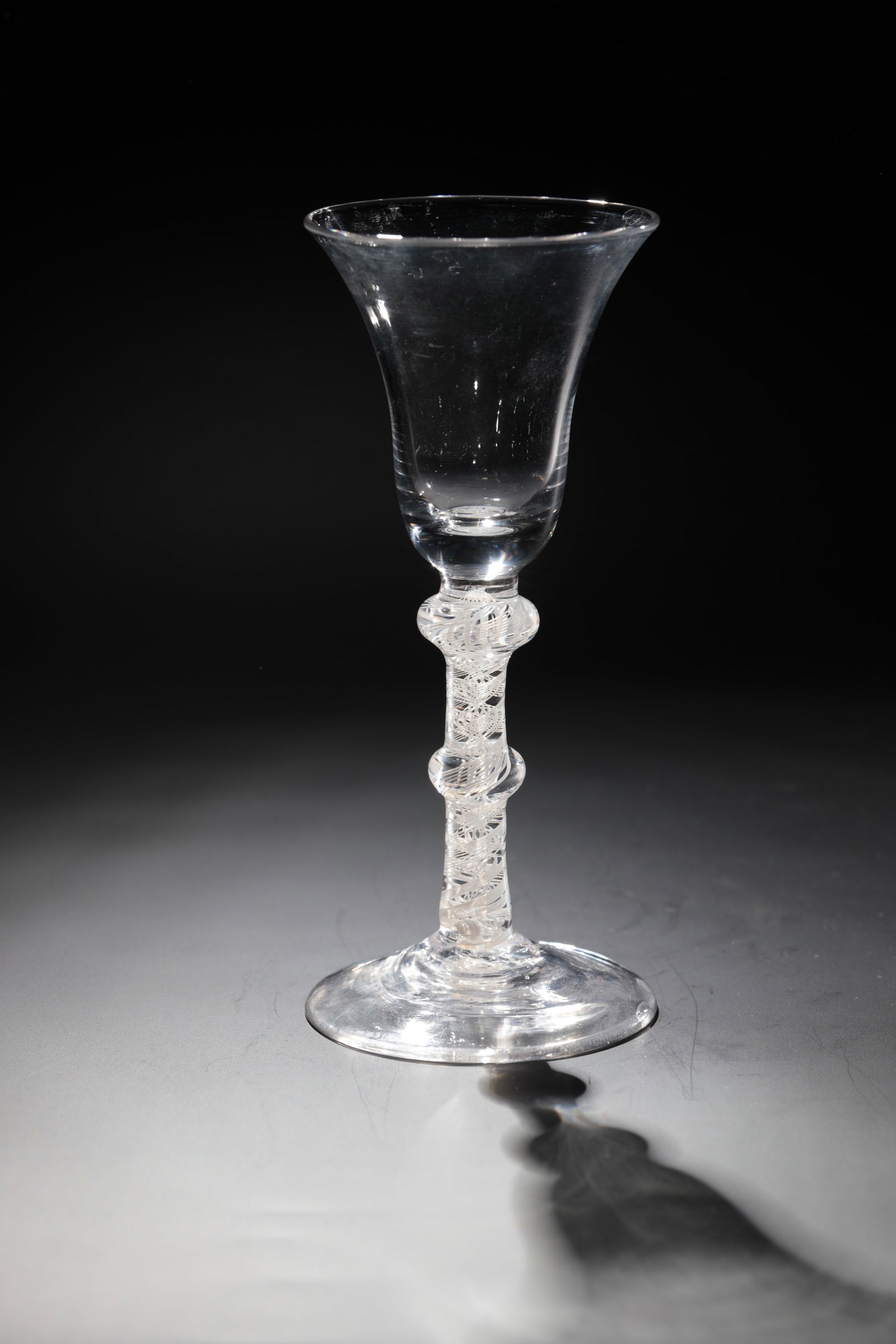 Filament glass: Thread glass England, 18th century. Disc base with tear-off. Upper with two nodes and spirally incorporated frosted glass threads. Bell-shaped cuppa. H. 17 cm