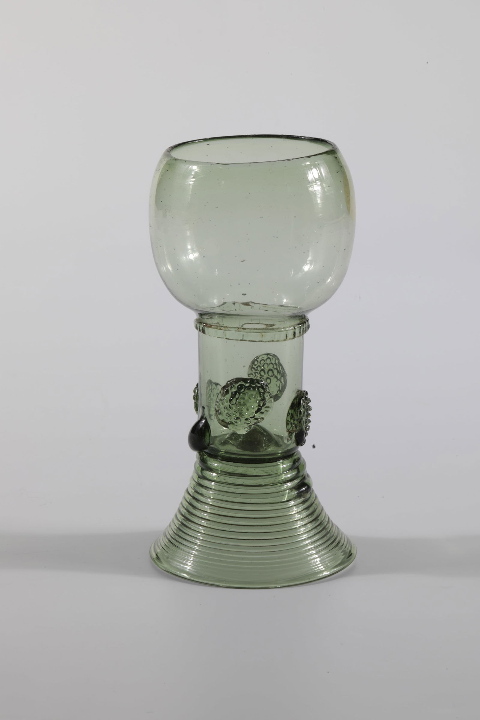 Romans: Roman German, 18th century Olive-green glass with tear-off. Spun trumpet foot. Hollow shaft open at the top with four applied berry nubs. Below the bulbous cuppa, a placed, pinched glass thread runs
