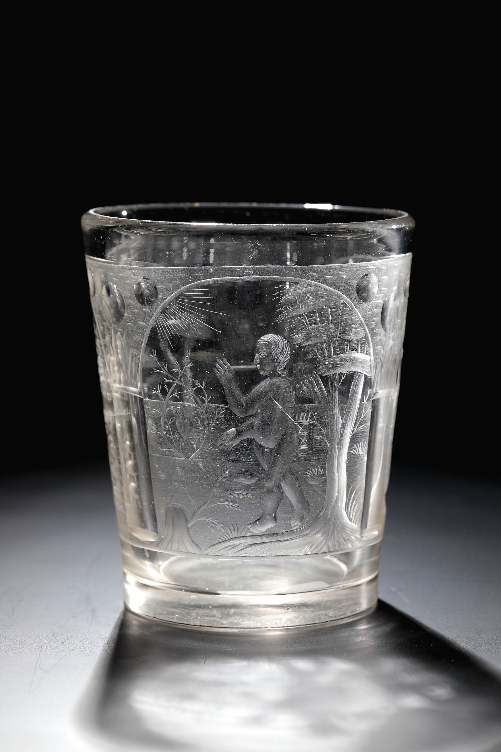 Mug with allegorical representations of love, masculinity and fertility: Goblet with allegorical depictions of love, masculinity and fertility Brandenburg or Bohemia, 17th century Colourless, thick-walled glass. On the conically widened wall, three arcades with