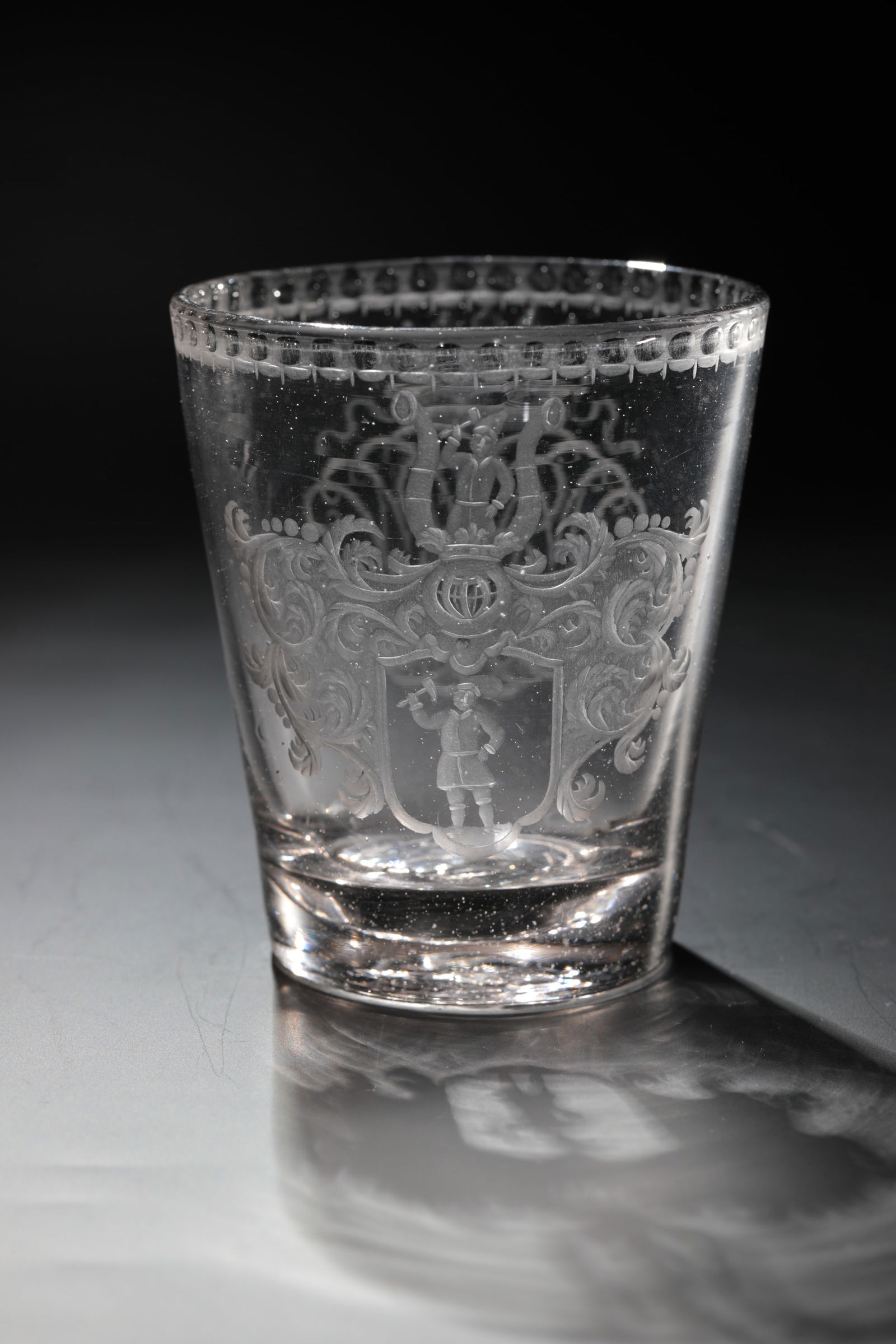 Coat of arms cup: Coat of arms cup Bohemia 17th / 18th century Grey-tinted glass with tear-off. Frontal on the conically widened wall, finely cut coat of arms with helmet ornament, ligature monogram crowned on the