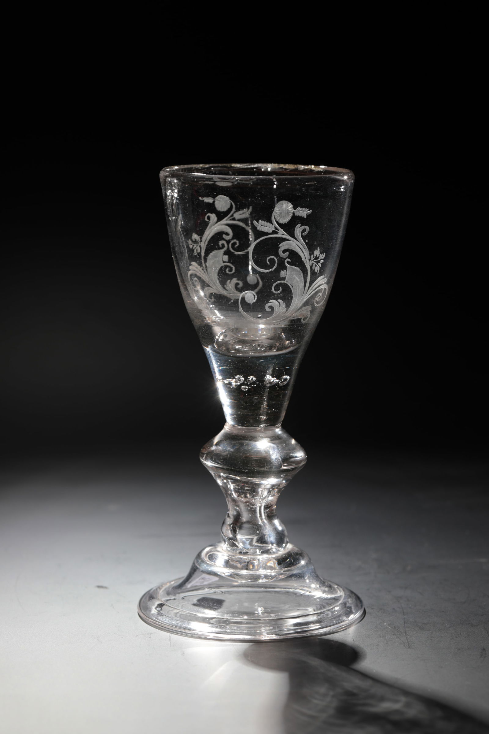 Chalice: Chalice Lauenstein, c. 1770 Colourless glass with tear-off. Shell foot with folded edge downwards. Baluster shaft with air bubble. In the base of the cuppa, seven pierced air beads. C-scrolls cut on