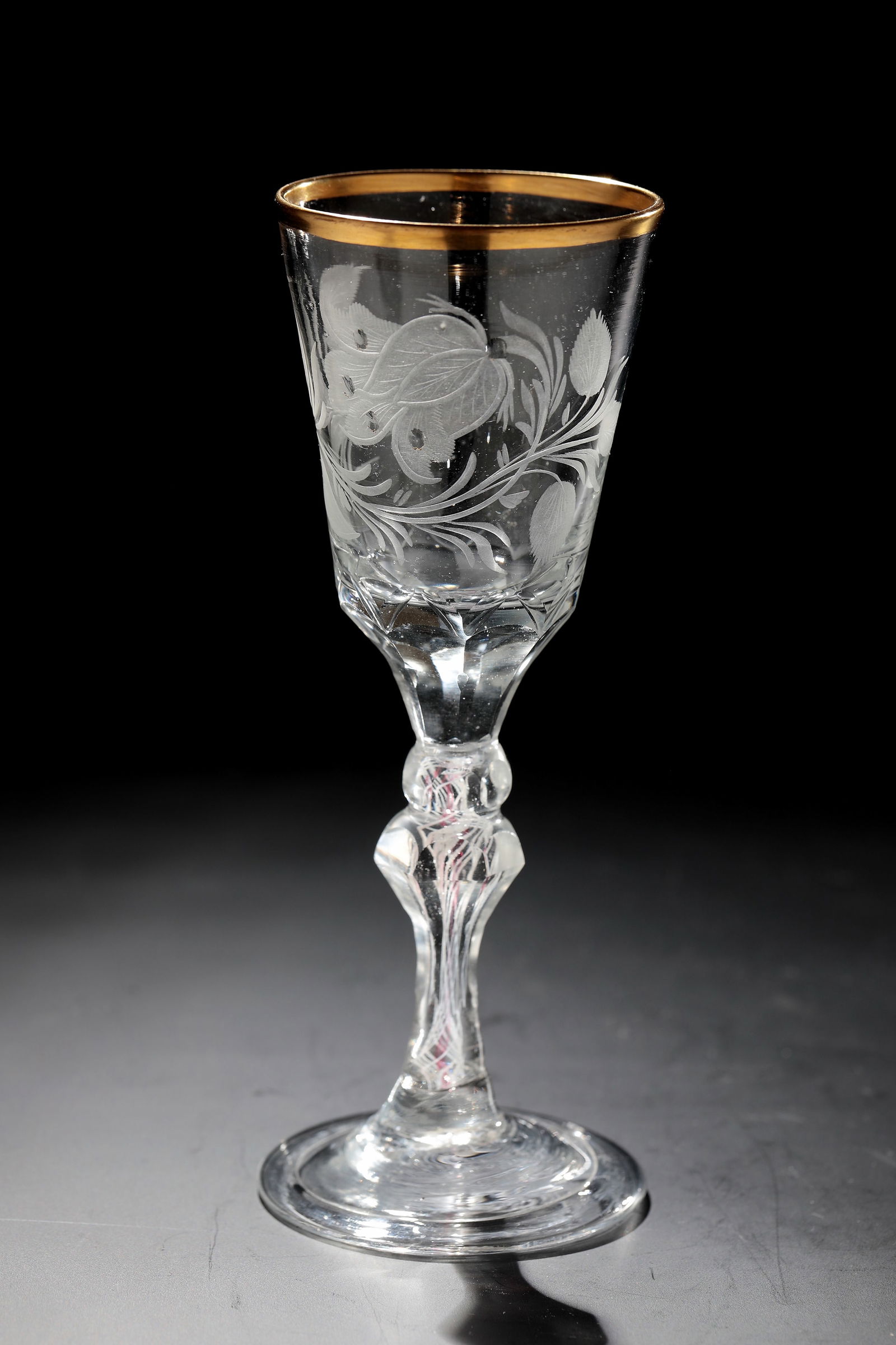 Small cup: Small cup Silesia, E. 18th century Colourless glass with tear-off. Disc base with the edge folded downwards. Faceted baluster shaft with nodus and incorporated milk and gold ruby threads. The base of