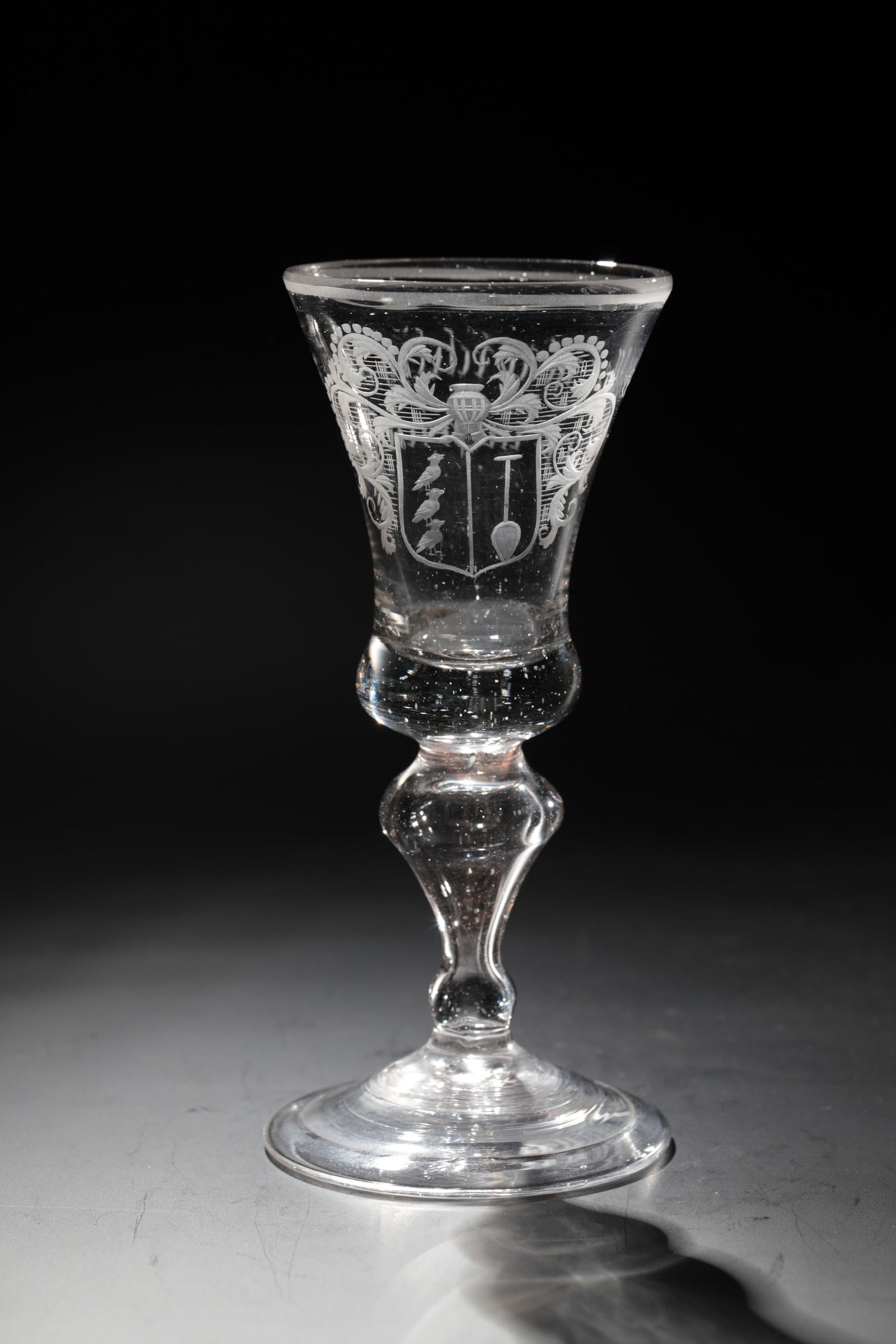 Coat of arms cup with motto: Coat of arms cup with motto German, 18th century Colourless glass with tear-off. Slightly rising disc base with folded edge downwards. Hollow baluster shaft. Coat of arms cut frontally on the bell-sha