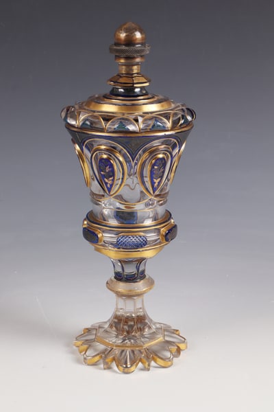 Lidded cup: Lidded goblet North Bohemia, c. 1840 Colourless glass, partly with cobalt blue overlay. Passively sharpened foot. Peeled shaft with disc nodus. Attachment of the bell-shaped cuppa with six high-cut