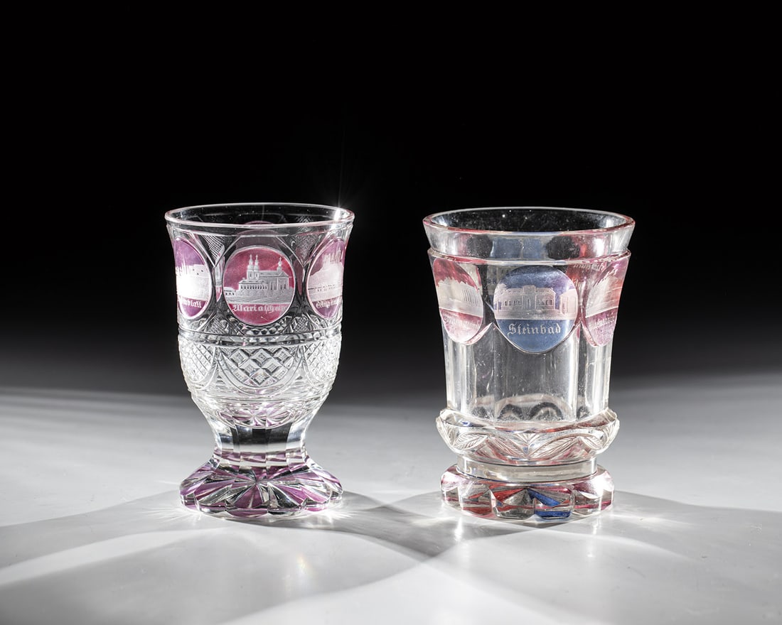 Two Mugs with Views of Teplice: Two beakers with views of Teplice Bohemia, dated 1836 and 1840 Colorless, richly cut glass with pink, purple and blue glaze. Views of Teplitz cut into medallions all around. H.12 and 13cm.