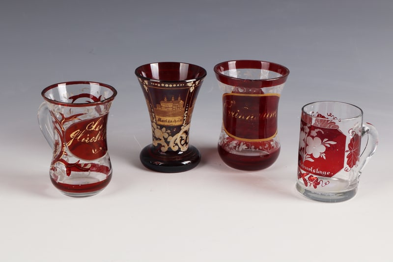 Four Cups: Four cups of Bohemia, mid-19th century Colourless, partly red-glazed glass with inscriptions: ''Sei Glücklich'', 'Zum Geburtstage'', ''Erinnerung'' and a cup with cut, gilded and inscribed views of T