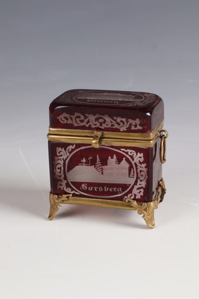 Small lidded box with views: Small lidded box with views of Bohemia, around 1860 Colourless, red-glazed glass. Rectangular body with frontal, reverse and lid views inscribed: ''Pillnitz'', ''Borsberg'' and ''Ruine''.