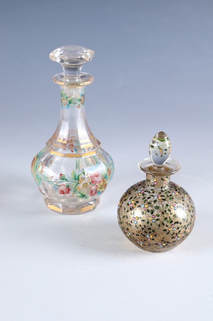 Two bottles with stoppers: Two flacons with stoppers 19th century Colourless, partly faceted cut glass with opaque or translucent enamel and gold painting: flowers, leaves and tendrils. A plug damaged. H. 8 or 13 cm