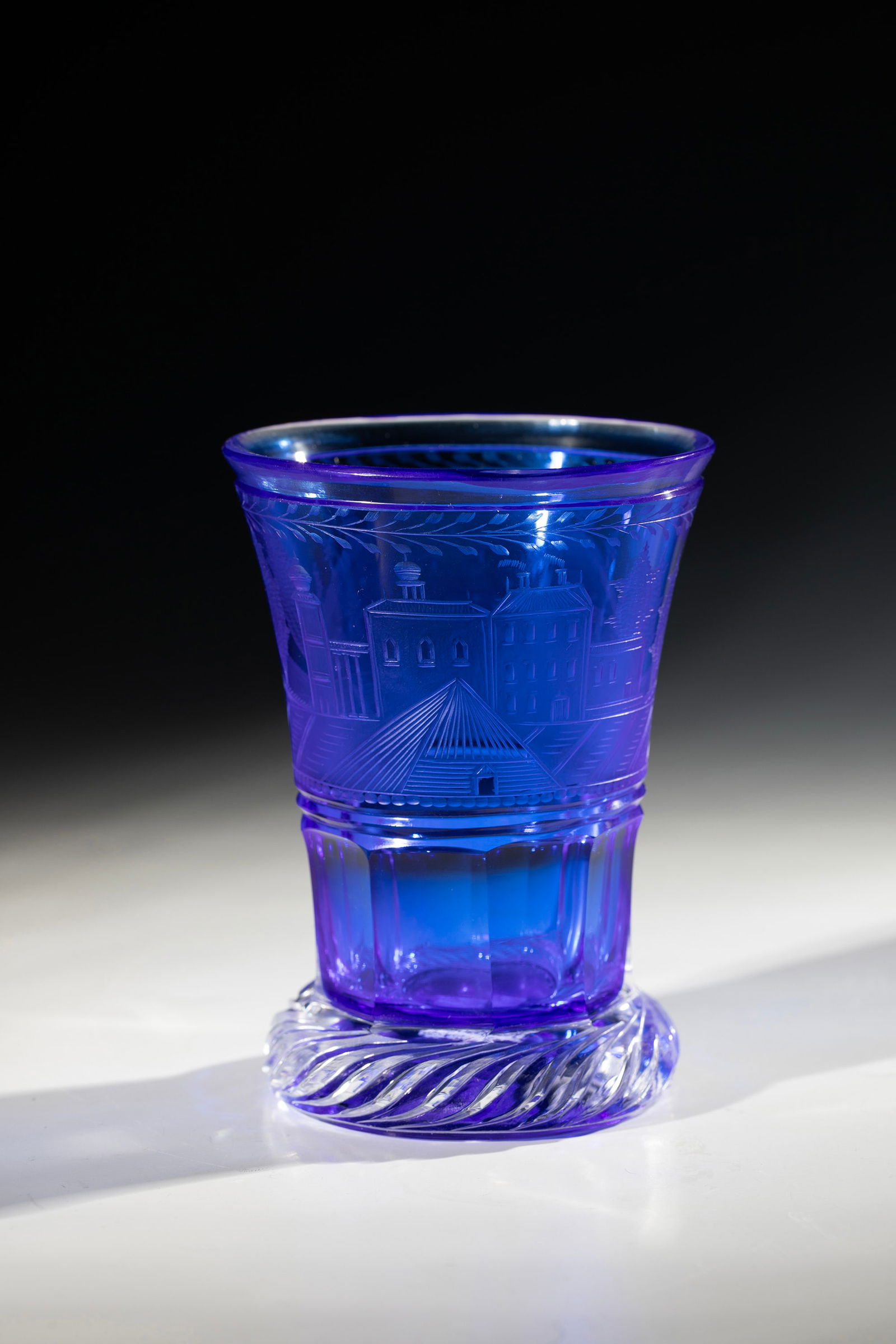 Ranft Mug: Ranft beaker Bohemia, 19th century Colourless glass with cobalt blue underlay. Ranft with turban cut. On the faceted wall at the base, architectural staffage cut all around in a park landscape.