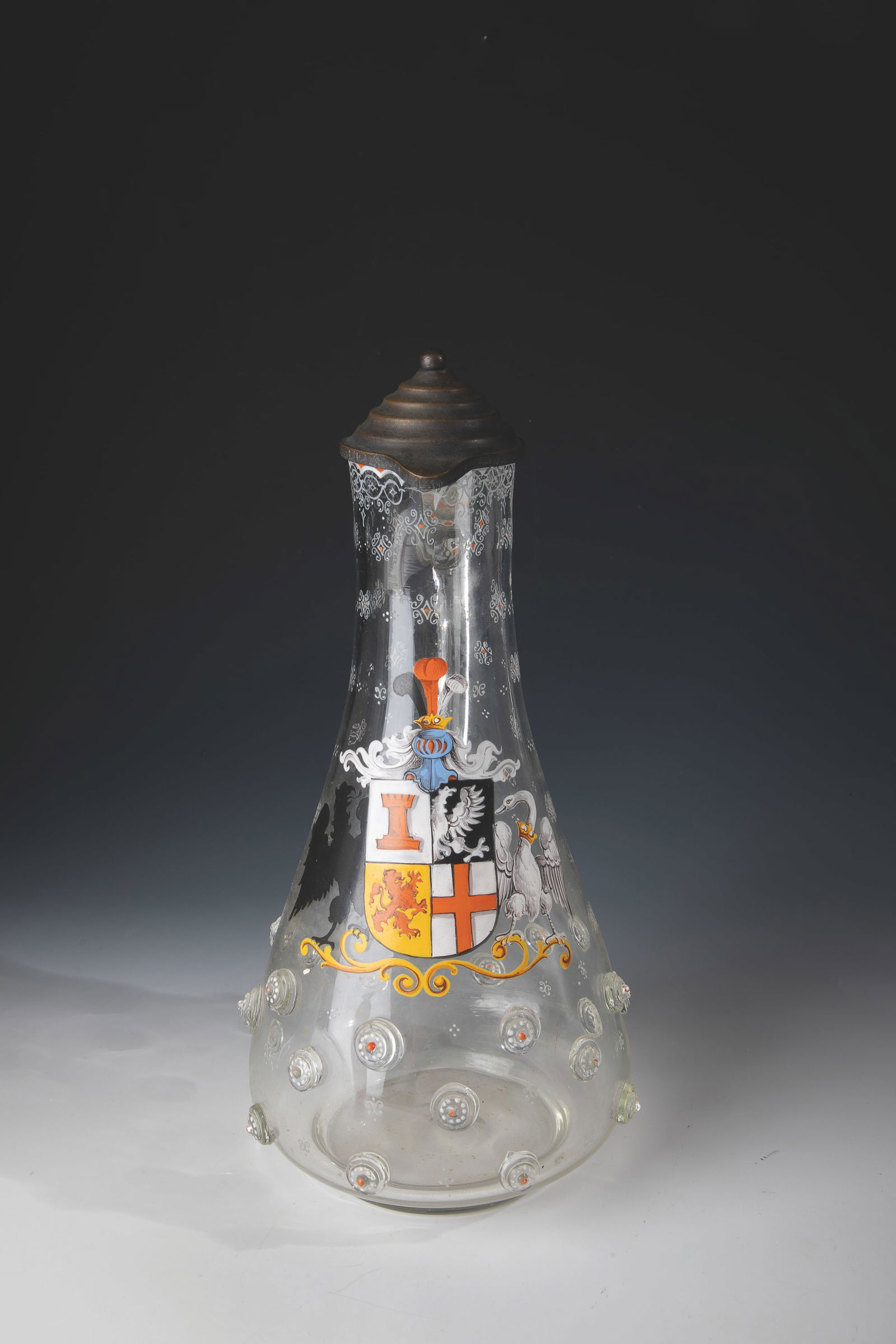 Lidded jug with coat of arms: Lidded jug with coat of arms E. 19th century: Colourless glass with polished demolition. In the lower part, three rows of applied nubs. Frontal coat of arms executed in polychrome enamel painting.