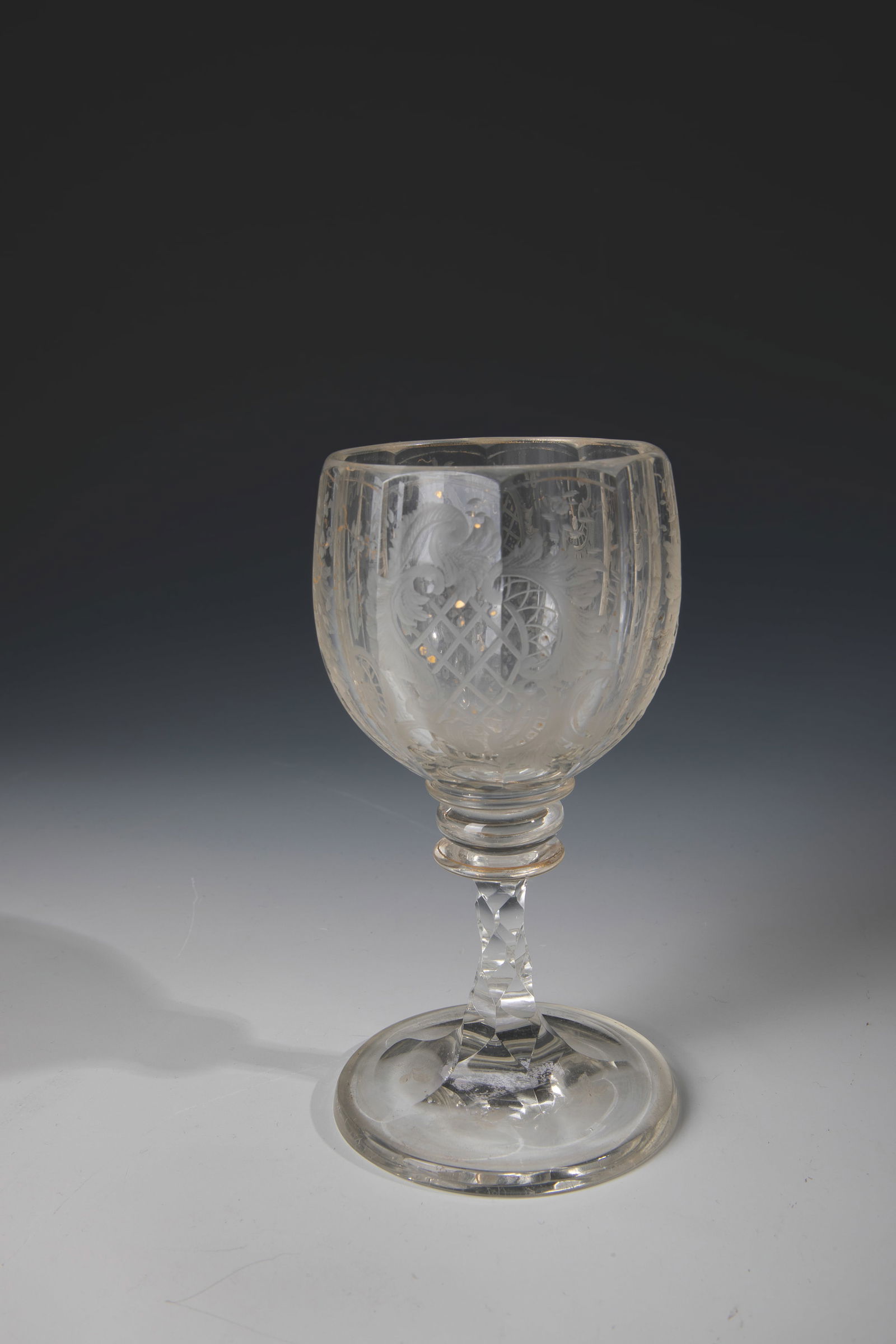 Cup: Trophy E. 19th century Colourless glass with rich cut decoration and rubbed gold painting: tendrils, C-scrolls, shellwork, flowers and coats of arms. H. 13 cm