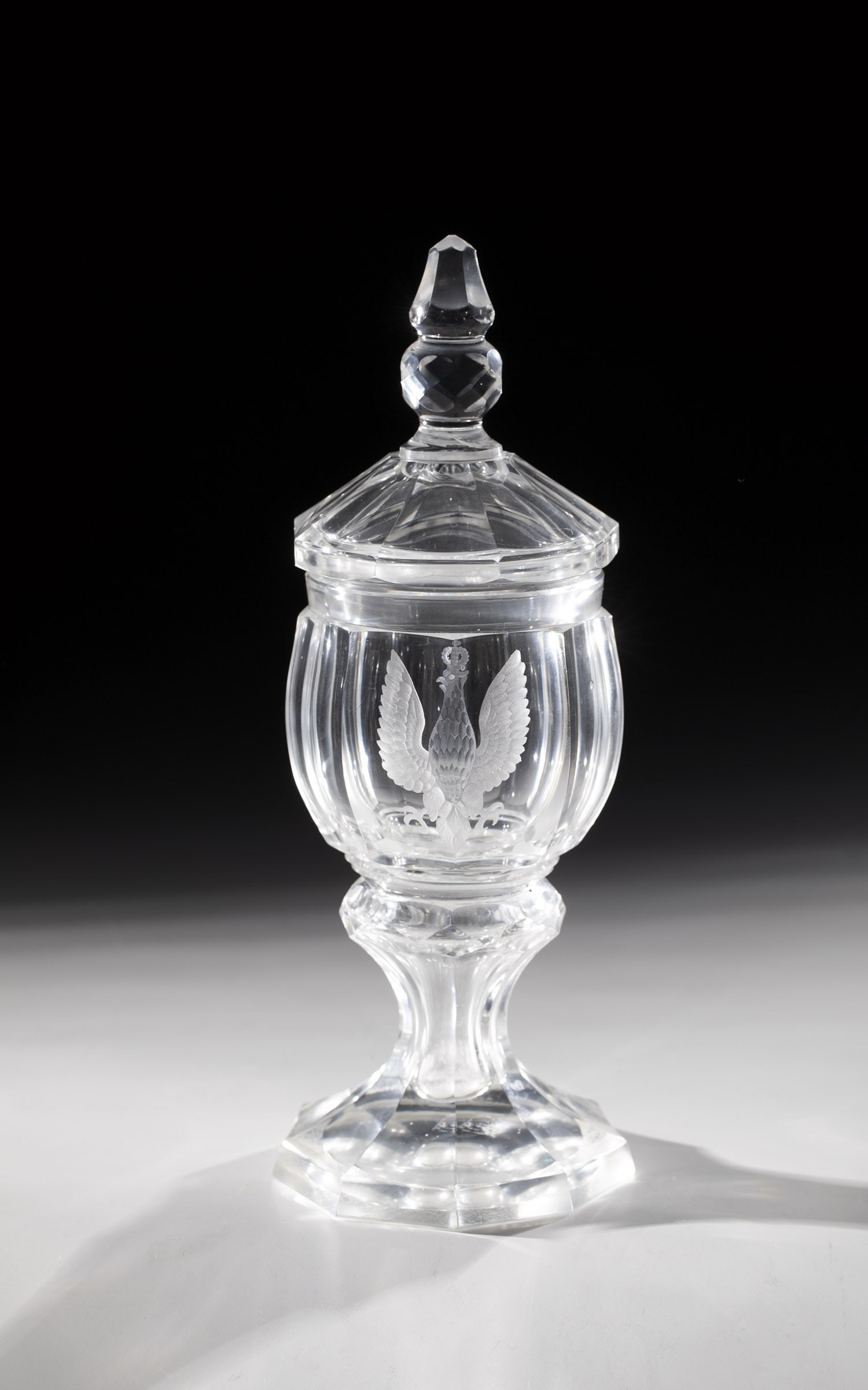 Lidded goblet with eagle: Lidded goblet with eagle Bohemia, 19th century Colourless, thick-walled glass, peeled nine times. Frontal low-cut, crowned eagle. Min. topping. H. 24 cm (with matching decorated lid)