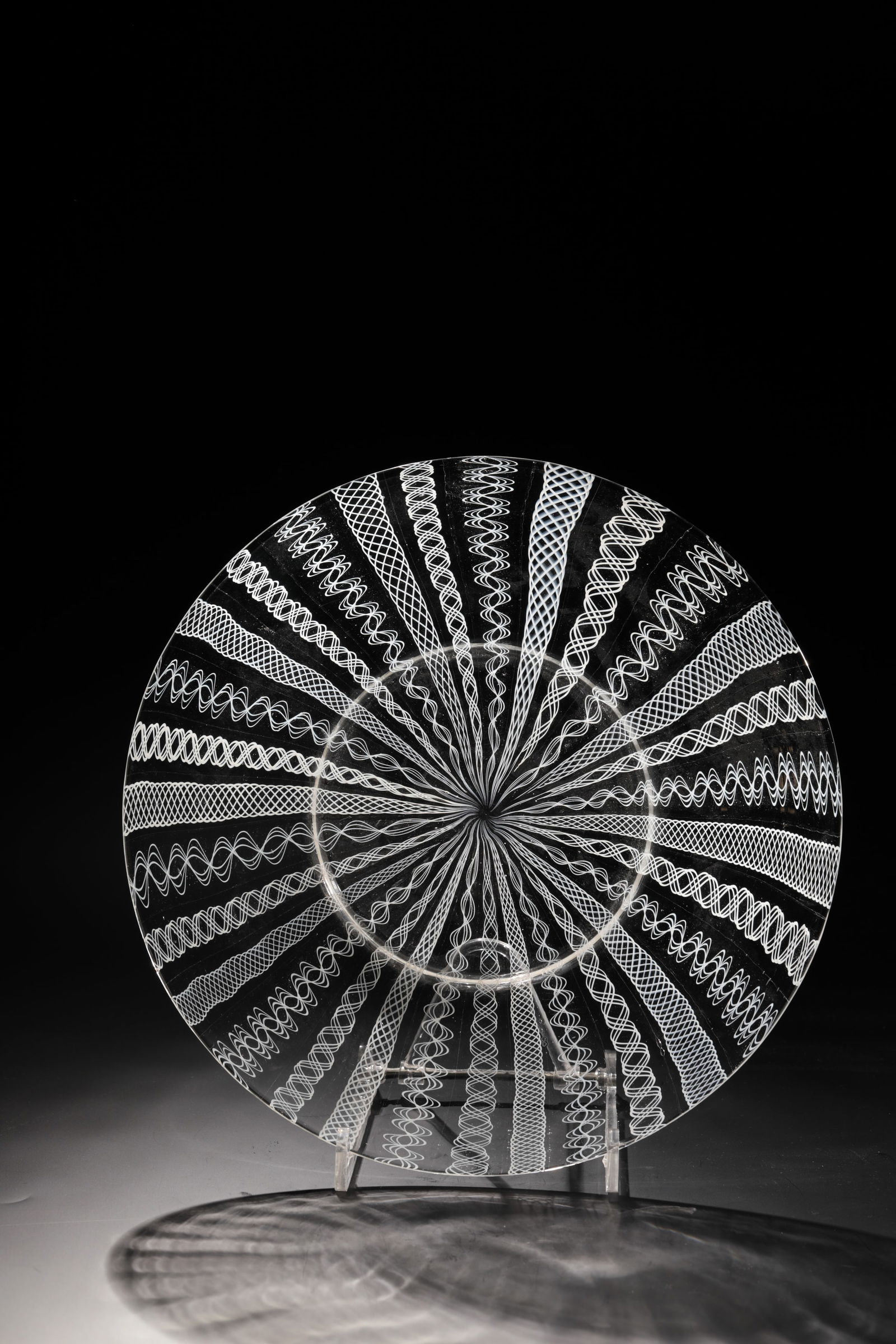 Latticinio Plate: Latticinio plate Rheinische Glashütten AG, Cologne-Ehrenfeld, around 1881 Colourless glass. Three different, alternating latticinio patterns made of white patterned rods. D: 29.5 cm.