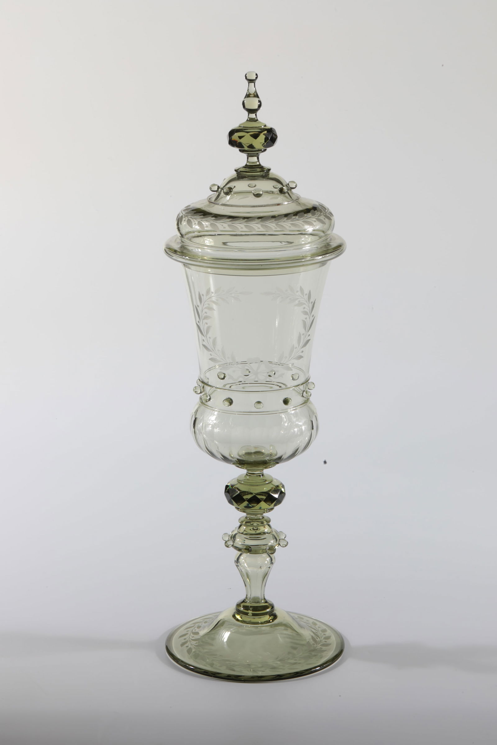 Large ''Mosler Cup'' with lid: Large ''Mosler Cup'' with lid Rheinische Glashütten AG, Cologne-Ehrenfeld, around 1881 Moss green glass. Melted beads and threads on lid and cup. Polished, laurel leaf engraving on the cuppa. H: