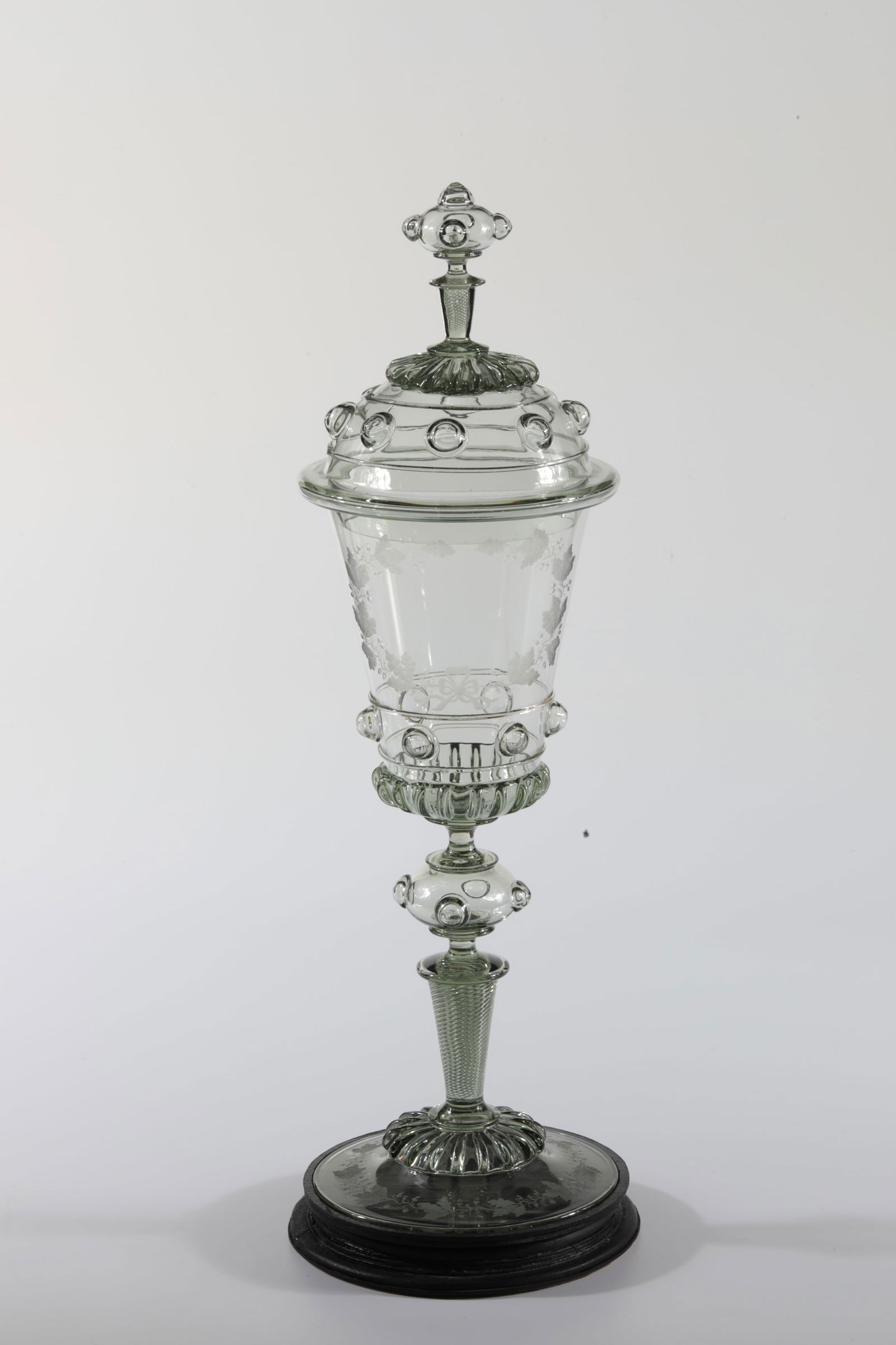 Large lidded goblet ''''Emanuel'' with pedestal: Large lidded goblet ''''Emanuel'' with pedestal Rheinische Glashütten AG, Cologne-Ehrenfeld, c. 1881 Light green glass. On disc base with ribbed rosette and on cuppa very finely cut oak leaves with b