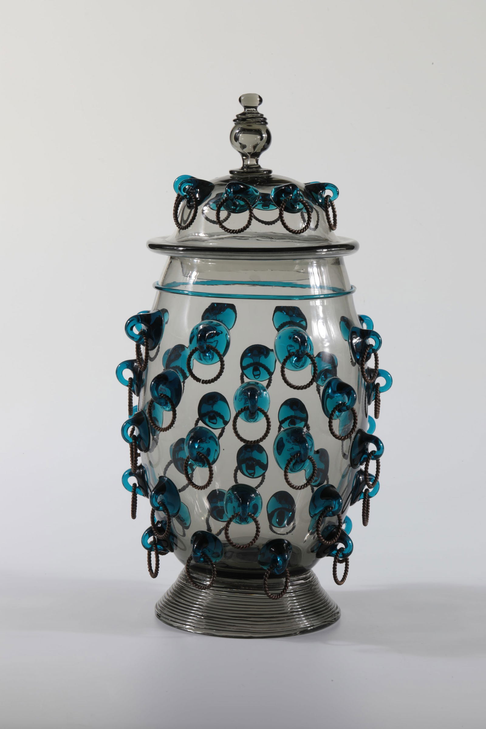 Large ring tankard with lid: Large ring tankard with lid Rheinische Glashütten AG, Cologne-Ehrenfeld, around 1881 Large ring tankard with lid. Green glass with folded thread and turquoise nubs with brass rings. Small stress