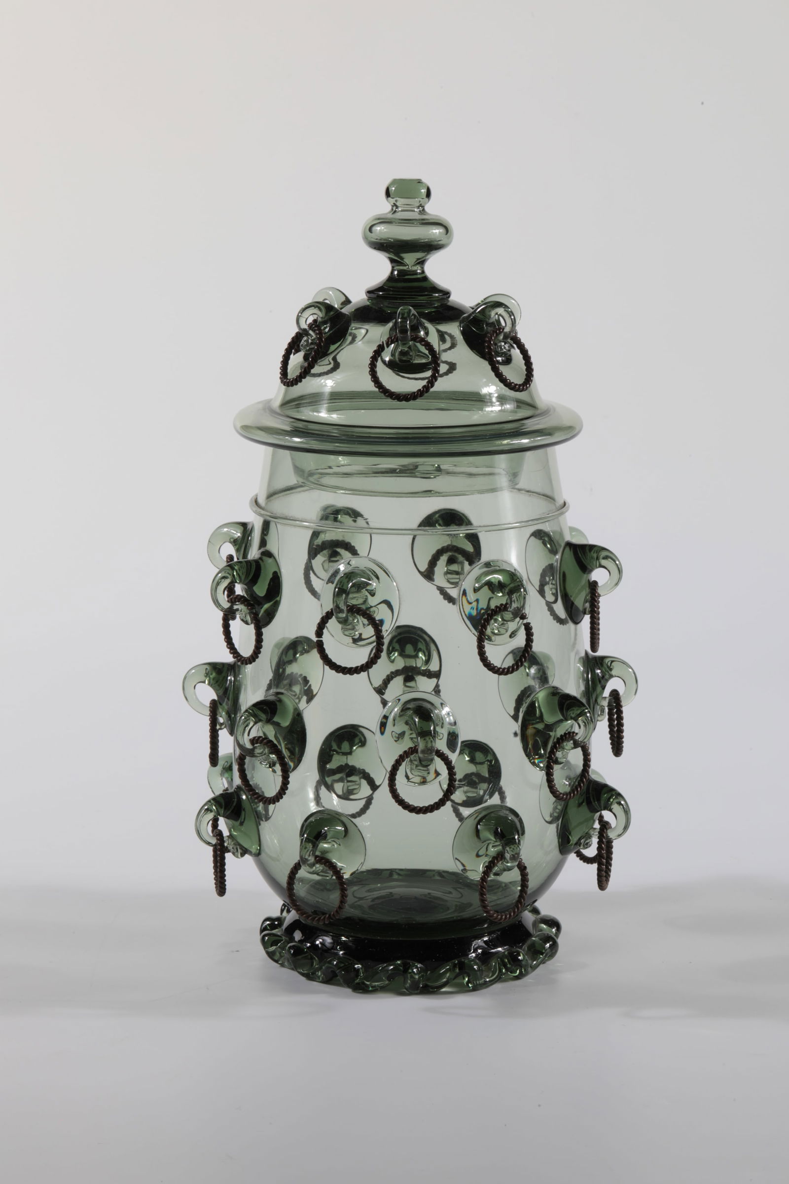 Small ringed tankard with lid: Small ringed tankard with lid Rheinische Glashütten AG, Cologne-Ehrenfeld, around 1881 Green glass, mould-blown, melting, metal rings. A ring on the lid is missing. H: 23 cm.