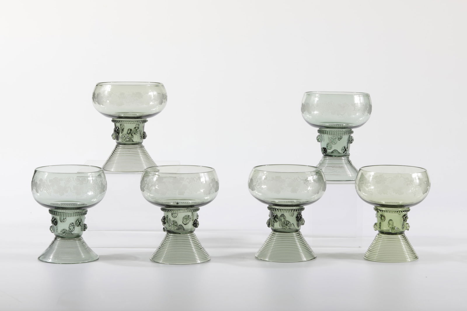 Six Hohlbein Romans: Six Hohlbein-Römer Rheinische Glashütten AG, Cologne-Ehrenfeld, around 1881 Antique green glass. Kuppa engraved with vine leaves, ribbed thread and eight small nubs. Foot spun. H: 9 cm.