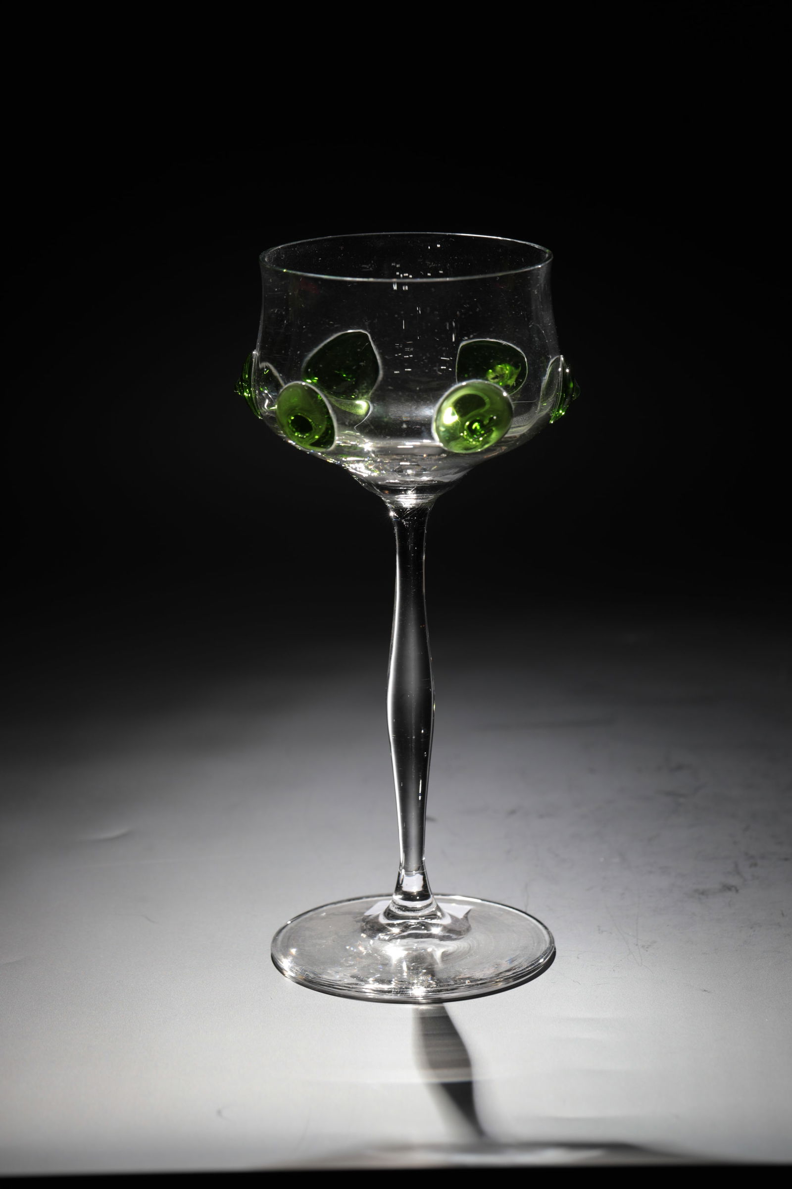 Goblet Margot: Goblet glass Margot Rheinische Glashütten AG, Cologne-Ehrenfeld, around 1881 Colourless glass. Optical cuppa with green dots, curved stem. H: 19 cm.