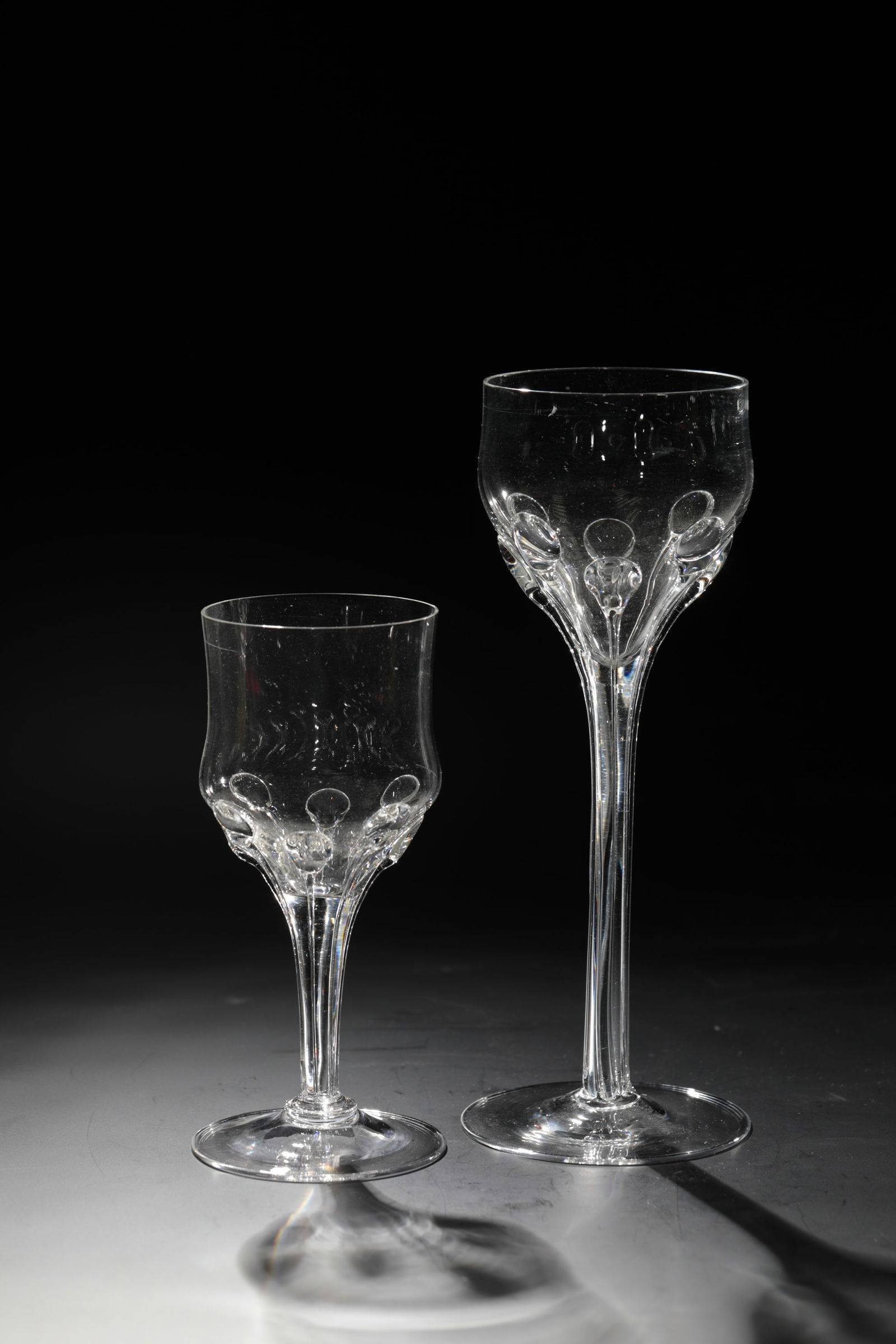 Two goblets: Two goblet glasses Rheinische Glashütten AG, Cologne-Ehrenfeld, around 1881 Colourless glass with applied, elongated, colourless drops from the tip end to the foot. H: 21 cm or 15 cm.