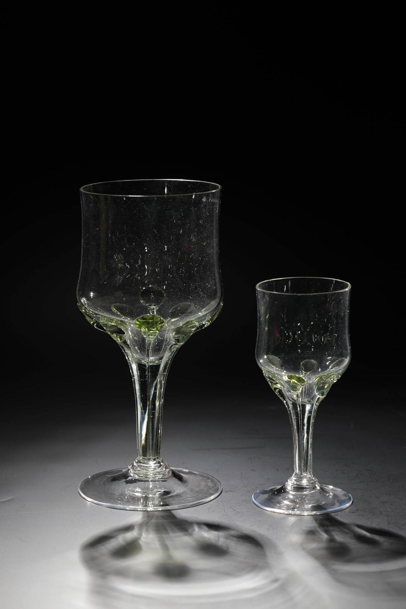 Two goblets: Two goblet glasses Rheinische Glashütten AG, Cologne-Ehrenfeld, around 1881 Colourless glass. Applied, elongated green drops from the tip end to the foot. H: 17.5 cm or 12 cm.
