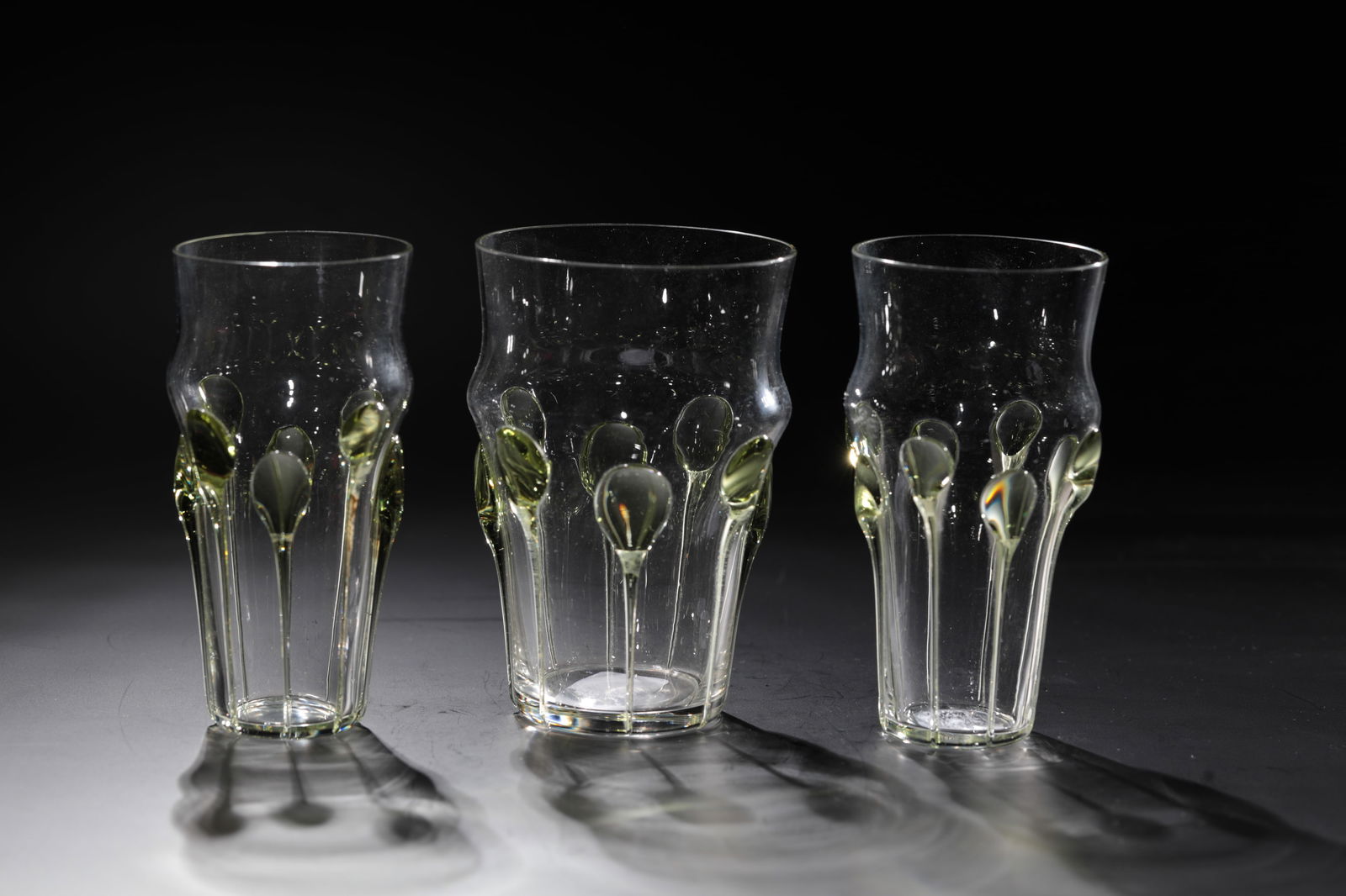 Three Champagne Tumblers: Three champagne tumblers Rheinische Glashütten AG, Cologne-Ehrenfeld, around 1881 Colourless glass with elongated green drops. H: 10.5 cm.