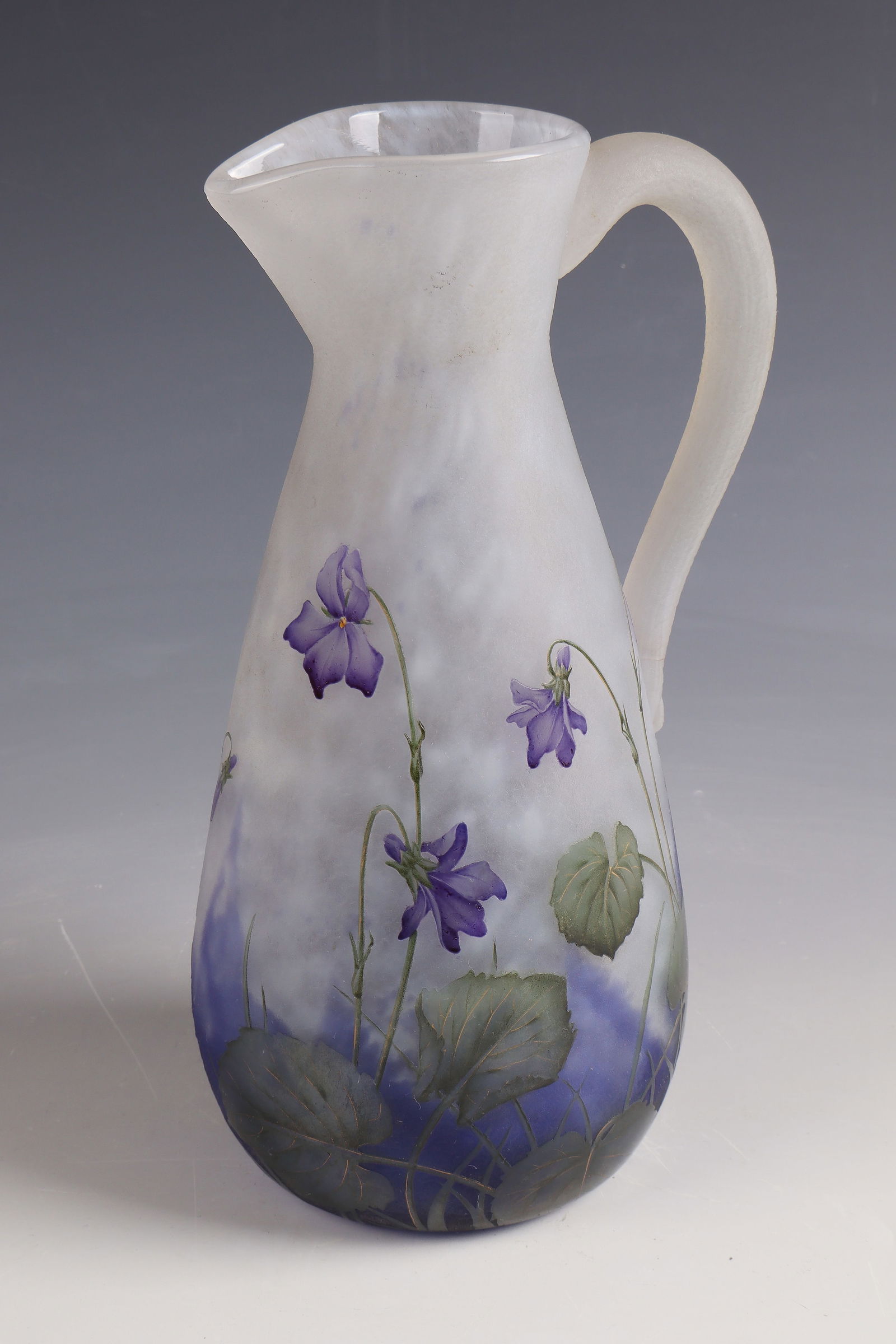 Jug of violets ''Violet'': Pitcher of violets ''Violet'' Daum Frères, Nancy, around 1900 Colourless glass with flaky powder melting in white and cobalt blue. Decorated in relief, etched and painted in colorful transparent
