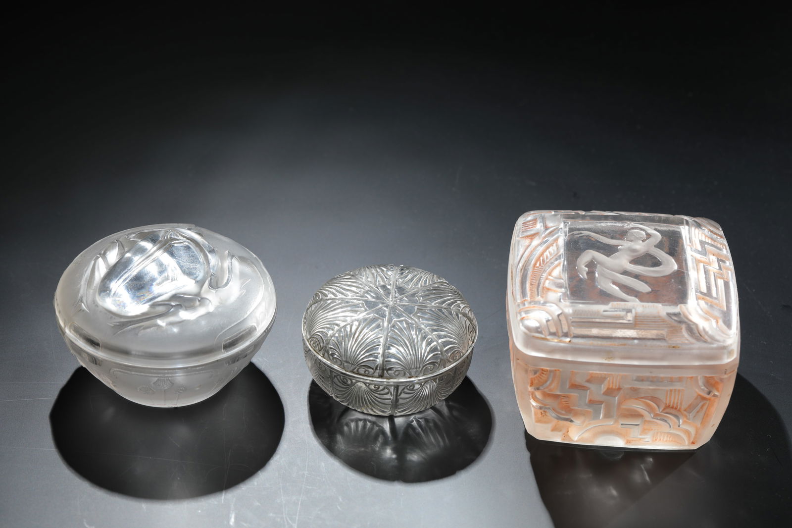 3 lidded jars ''Coquilles'' - ''Scarabée'' for L.T. Piver: 3 lidded jars ''Coquilles'' - ''Scarabée'' for L.T. Piver René Lalique, Wingen - sur - Moder, 1920 and 1922 Colourless glass, moulded, partly brown or black-grey patinated, refinished by polish.